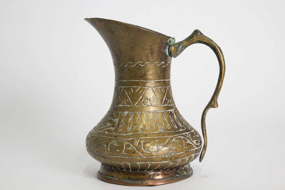 Antique 19th century Qajar Middle Eastern brass sharbat jug with Thuluth calligraphic script. An early 19th century Qajar brass jug. Finely engraved with detailed patterns and Thuluth style calligraphic script. The handle is brazed to the the main