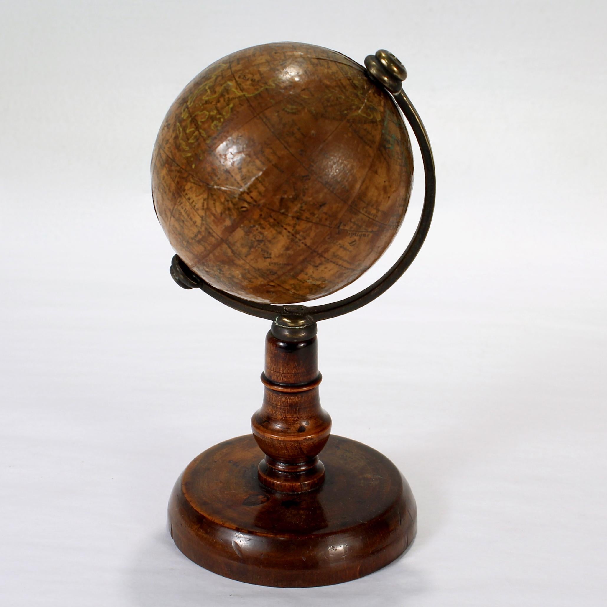 Un globe miniature ancien de l'édition française.

Par C.I.C..

Sur un support en bois tourné avec un demi-méridien en laiton non calibré. 

Le globe est marqué d'une étiquette intégrale indiquant 