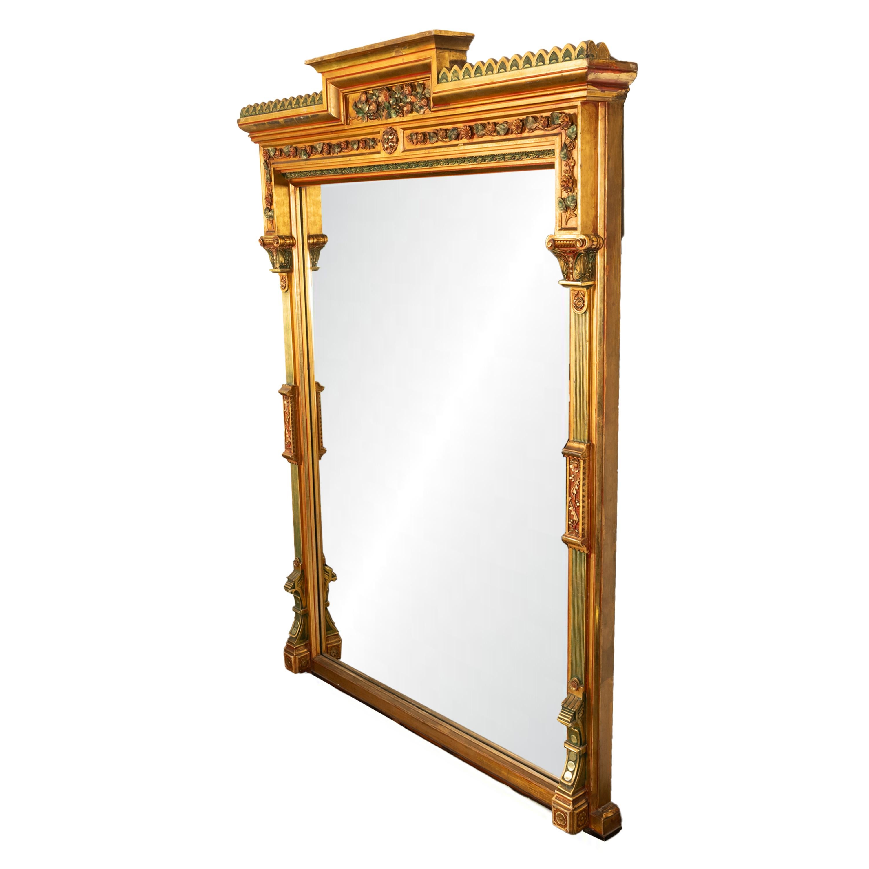 Un monumentale specchio a figura intera in legno dorato americano, New York, circa 1860.

Questo squisito specchio ha una corona ogivale a gradini fiancheggiata da un bordo merlato, sotto c'è un pannello floreale in rilievo con doratura tricolore e