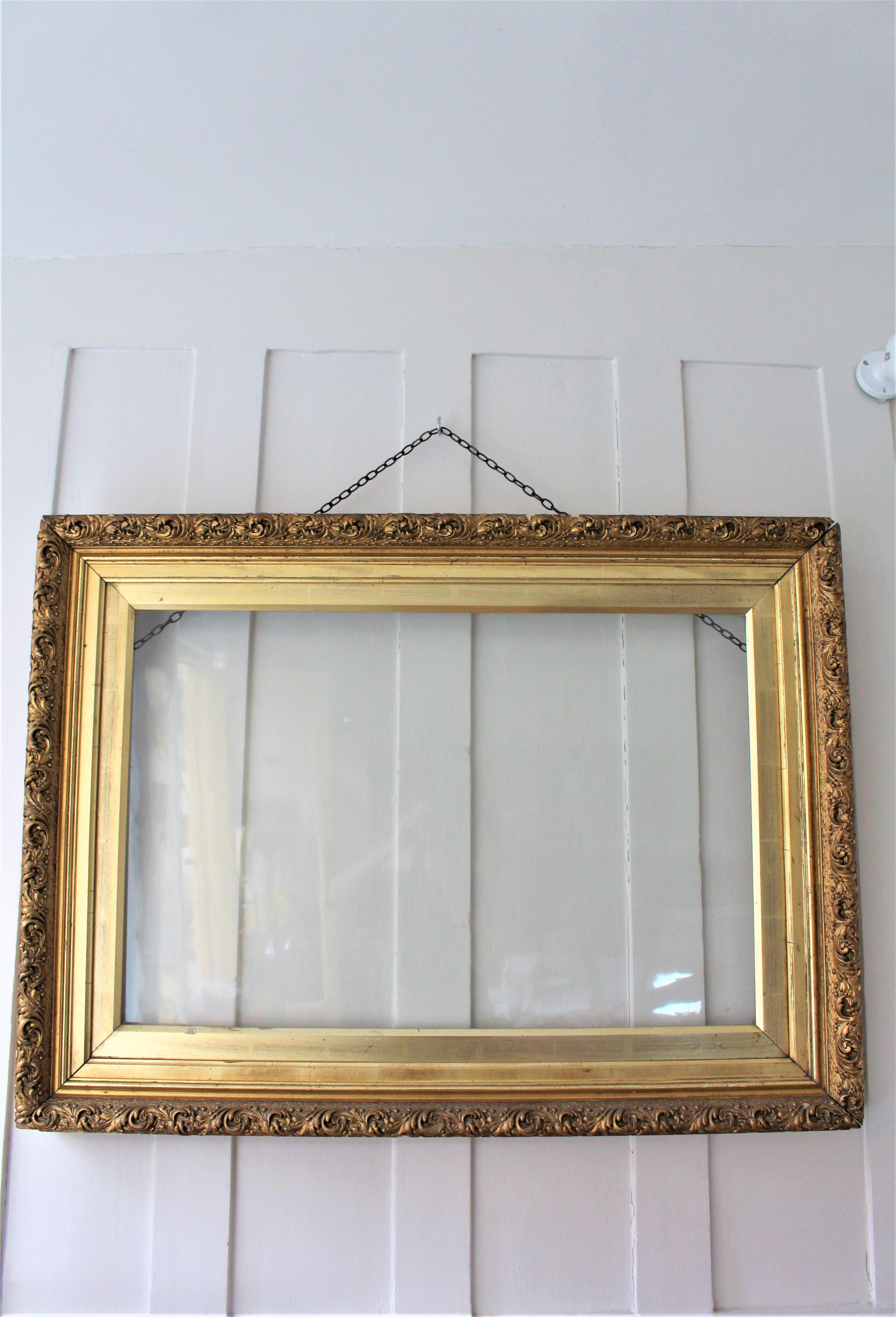 Antique giltwood frame with original rippled glass, gilt mount and chain,
circa 19th century.

Beautiful ornate picture/ painting frame with carved foliate.
This frame could be turned into a mirror with a bevel glass, which would be