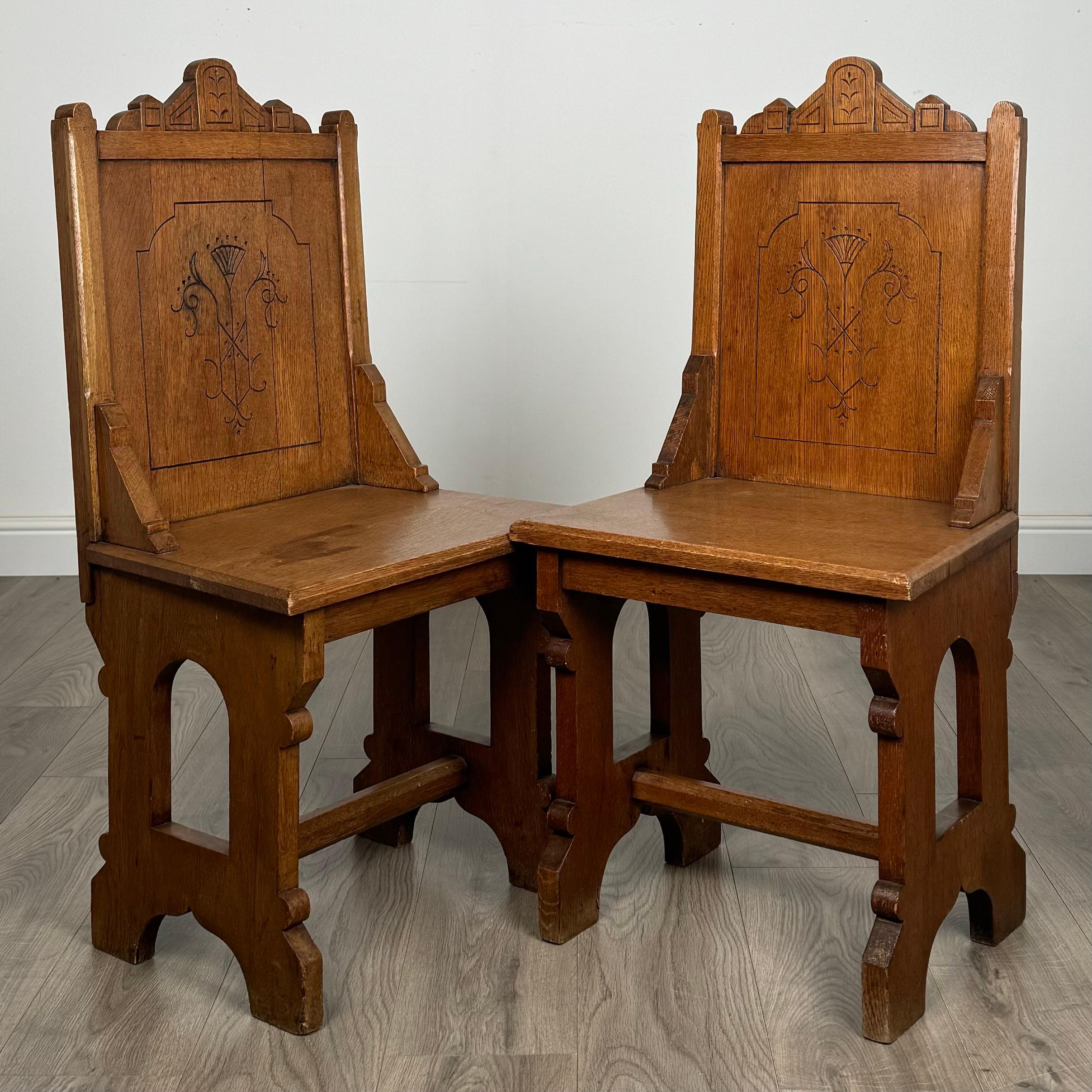 Une paire de chaises de salle en chêne du XIXe siècle, conçues dans un style gothique saisissant, présente des dossiers joliment décorés qui ajoutent une touche de charme historique. Les chaises présentent une conception solide et robuste, reflétant