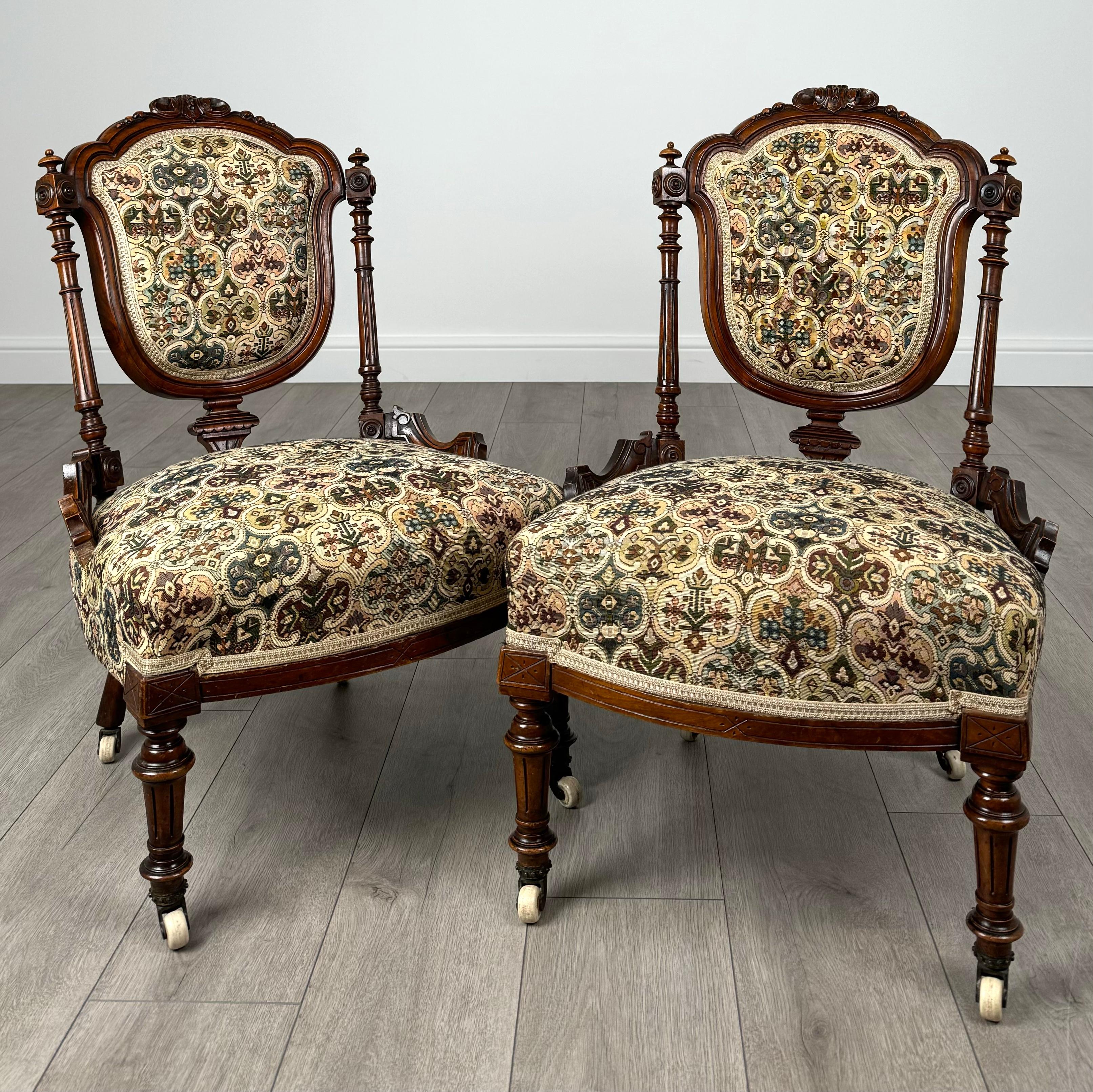 Este antiguo par de sillones victorianos del siglo XIX en nogal son un impresionante testimonio de la elegancia y la artesanía de su época. Las sillas presentan una magnífica tapicería de tapiz, con intrincados dibujos y ricos colores que