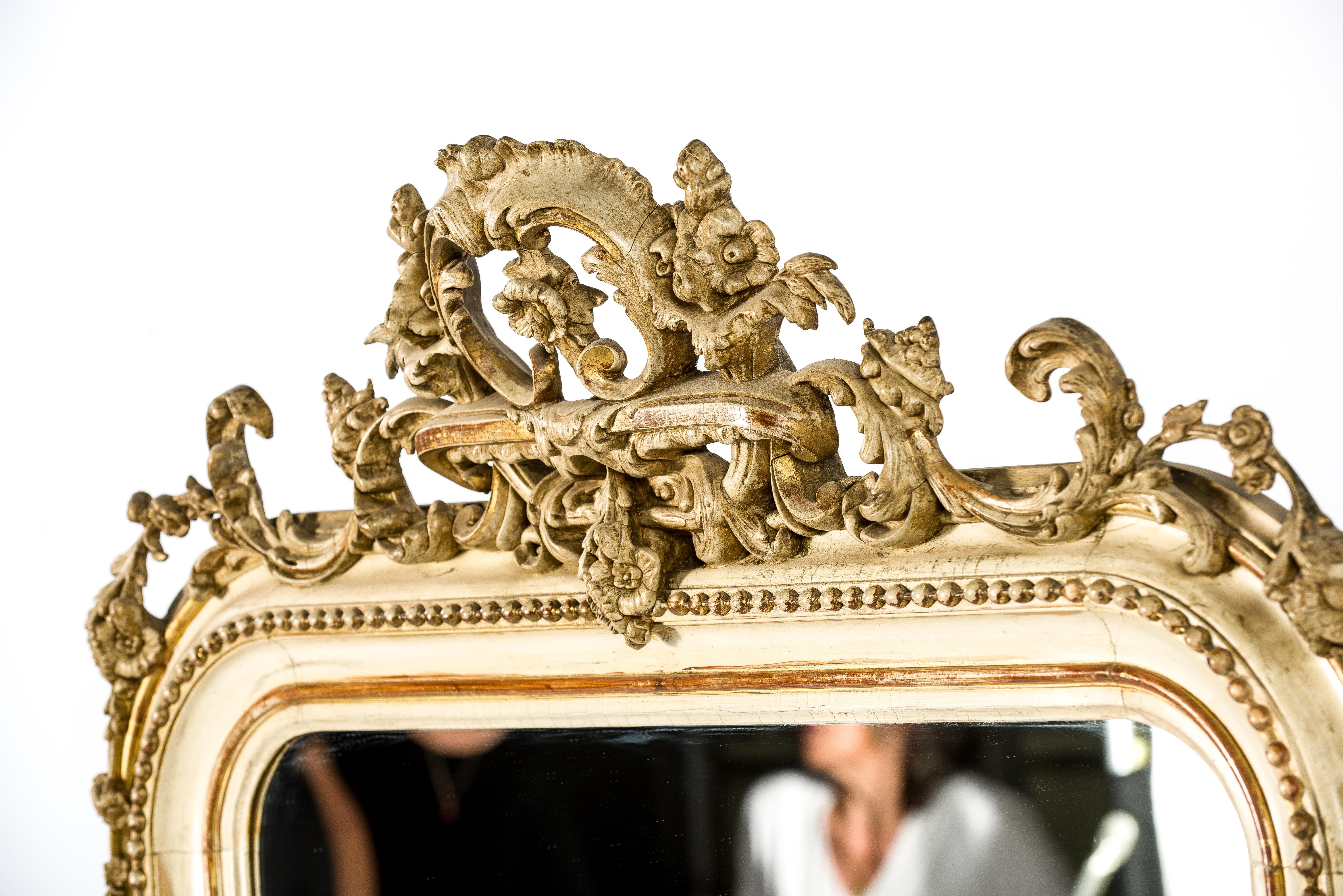 Un beau miroir ancien originaire de France, vers 1860. Le miroir présente les angles supérieurs arrondis typiques des miroirs français de Louis Philippe. Le miroir est orné d'une riche crête et d'ornements très détaillés dans les deux coins