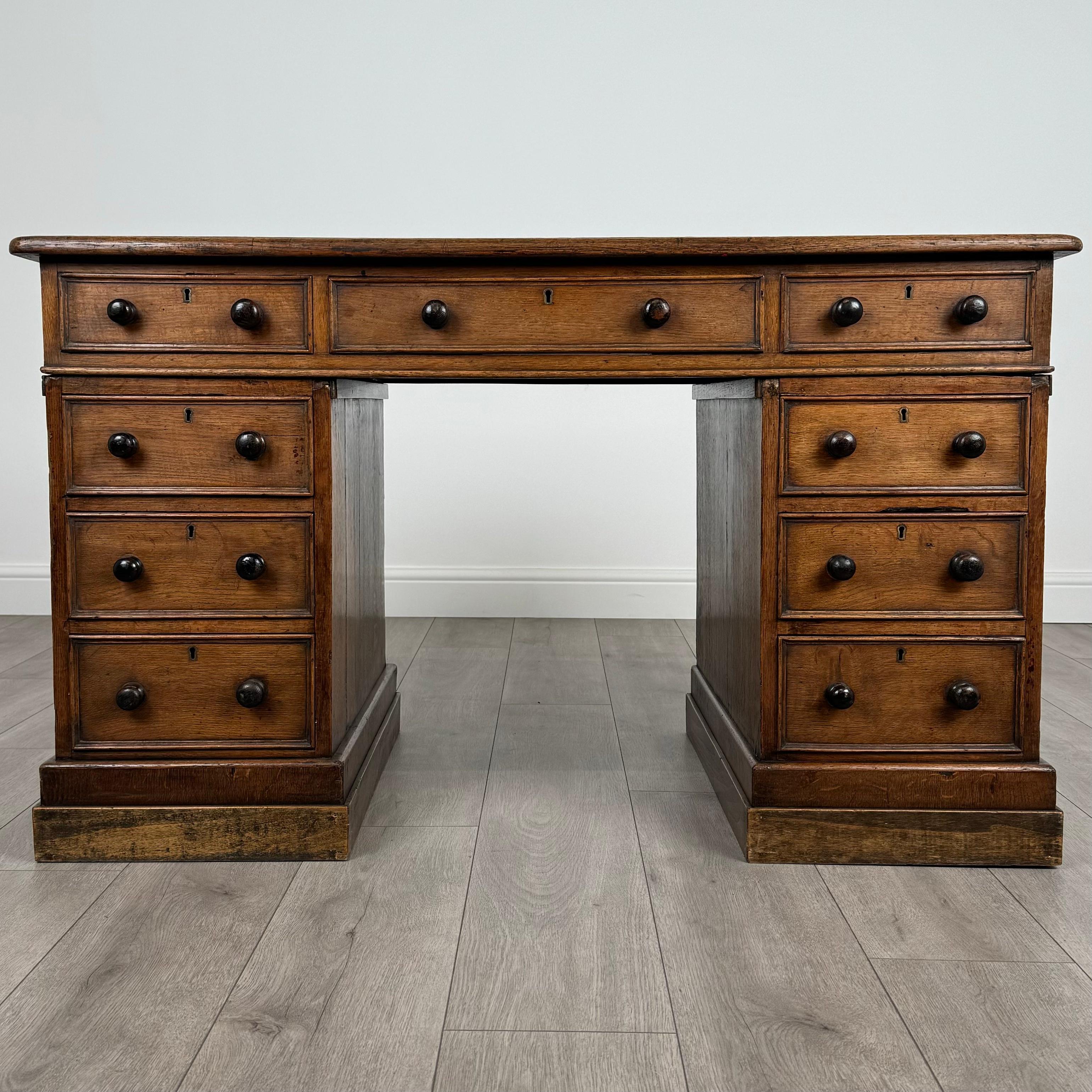 This stunning 19th-century pedestal desk, crafted from solid oak, is a perfect example of both functionality and elegance. 
Standing on a plinth base, the desk is in good condition and retains its original charm. It can be easily disassembled into