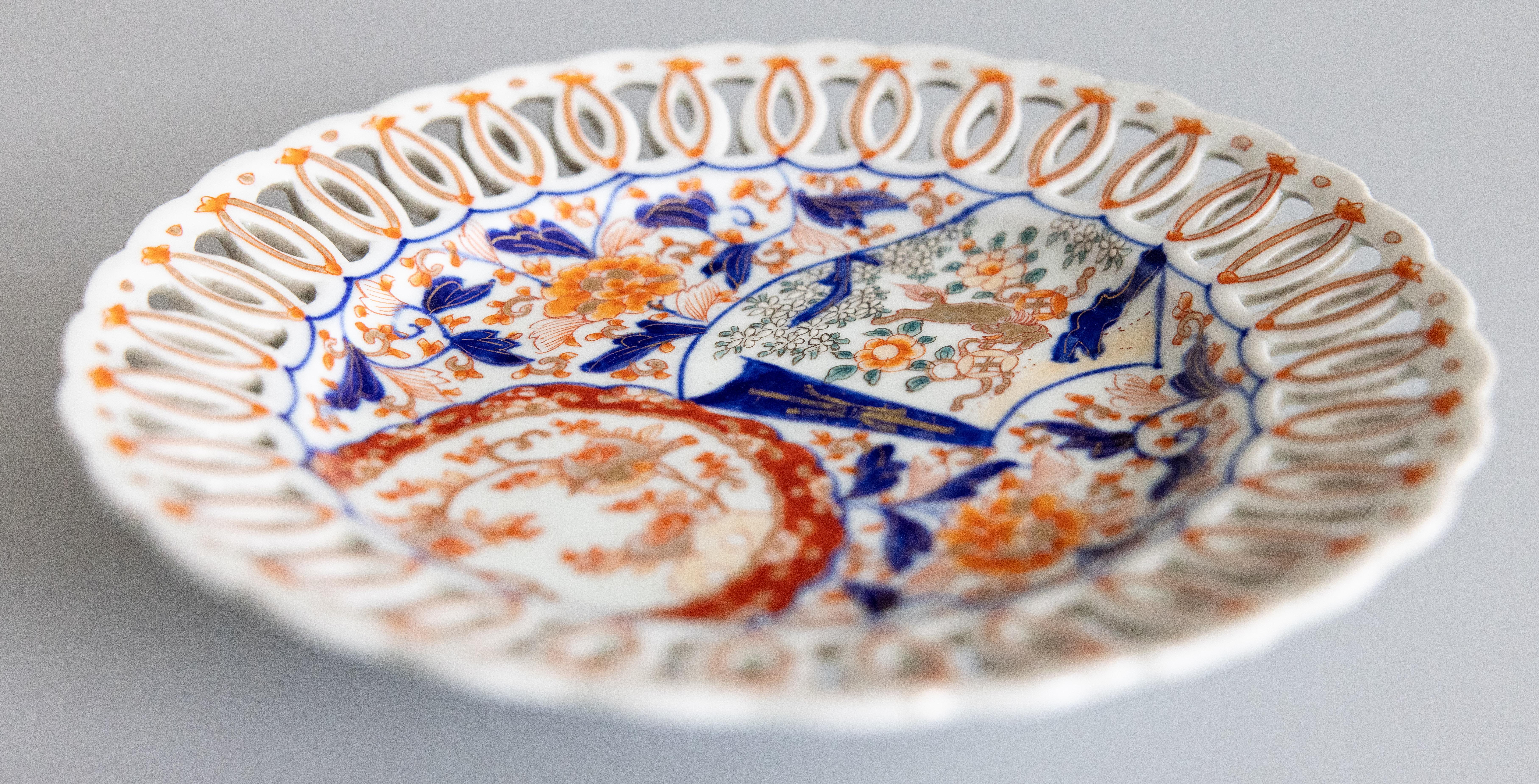 Magnifique assiette Imari antique du 19ème siècle avec un bord réticulé. Des oranges, des bleus et des verts éclatants sont à l'honneur. Le centre de l'assiette représente une gerbe de fleurs peinte à la main et des barrières de jardin.