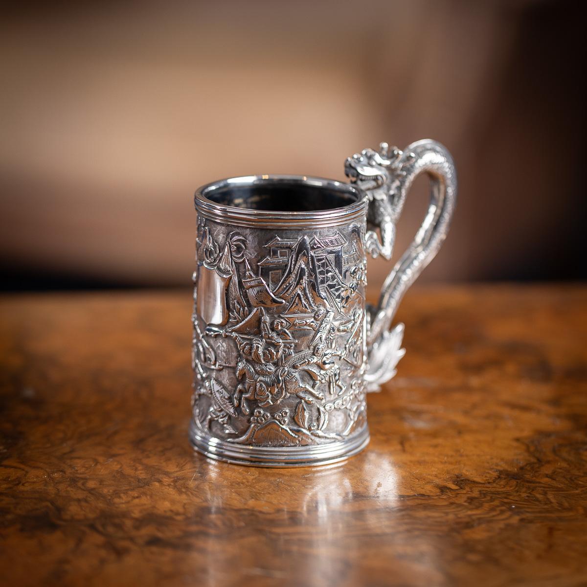 Ancienne tasse en argent massif d'exportation chinoise du 20e siècle, de forme effilée, les côtés sont magnifiquement décorés en relief d'une scène de guerriers au combat, très nette et détaillée, centrée sur un cartouche vide et façonné. La poignée