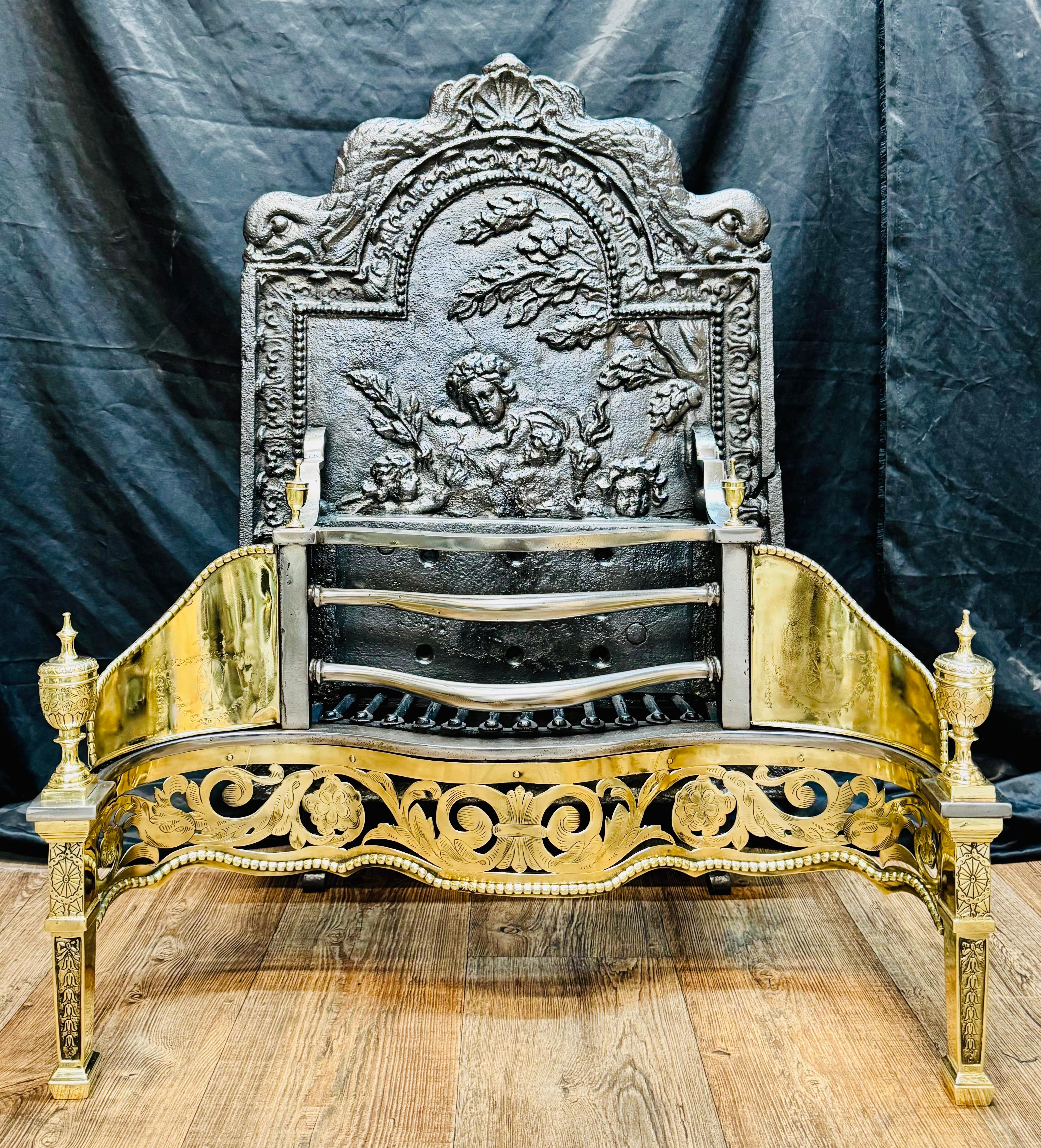 Un grande e insolitamente alto caminetto a serpentina in ottone lucido del XIX secolo, con elaborate terminazioni a urna incise, il tutto sostenuto da gambe affusolate. Al centro, un grembiule in ottone serpeggiante traforato con incisioni di volute