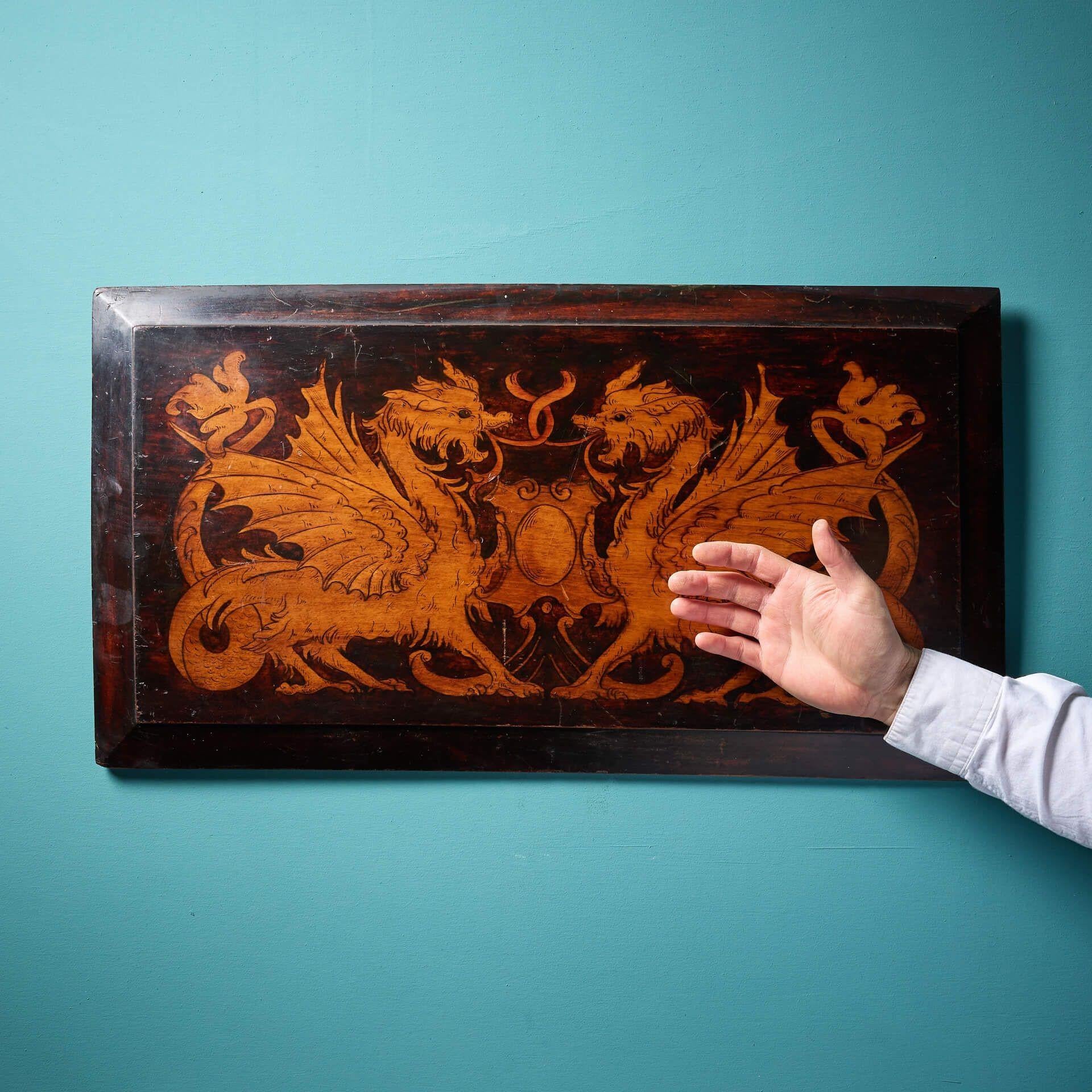 Ein antikes, handgefertigtes Regency-Wappen aus dem 19. Jahrhundert auf einer hölzernen Wandtafel.

Das Wappen zeigt ein hübsches Paar sich spiegelnder Drachen mit kunstvollen Schwänzen und Flügeln und einem schlichten Schild in der Mitte.

Mit