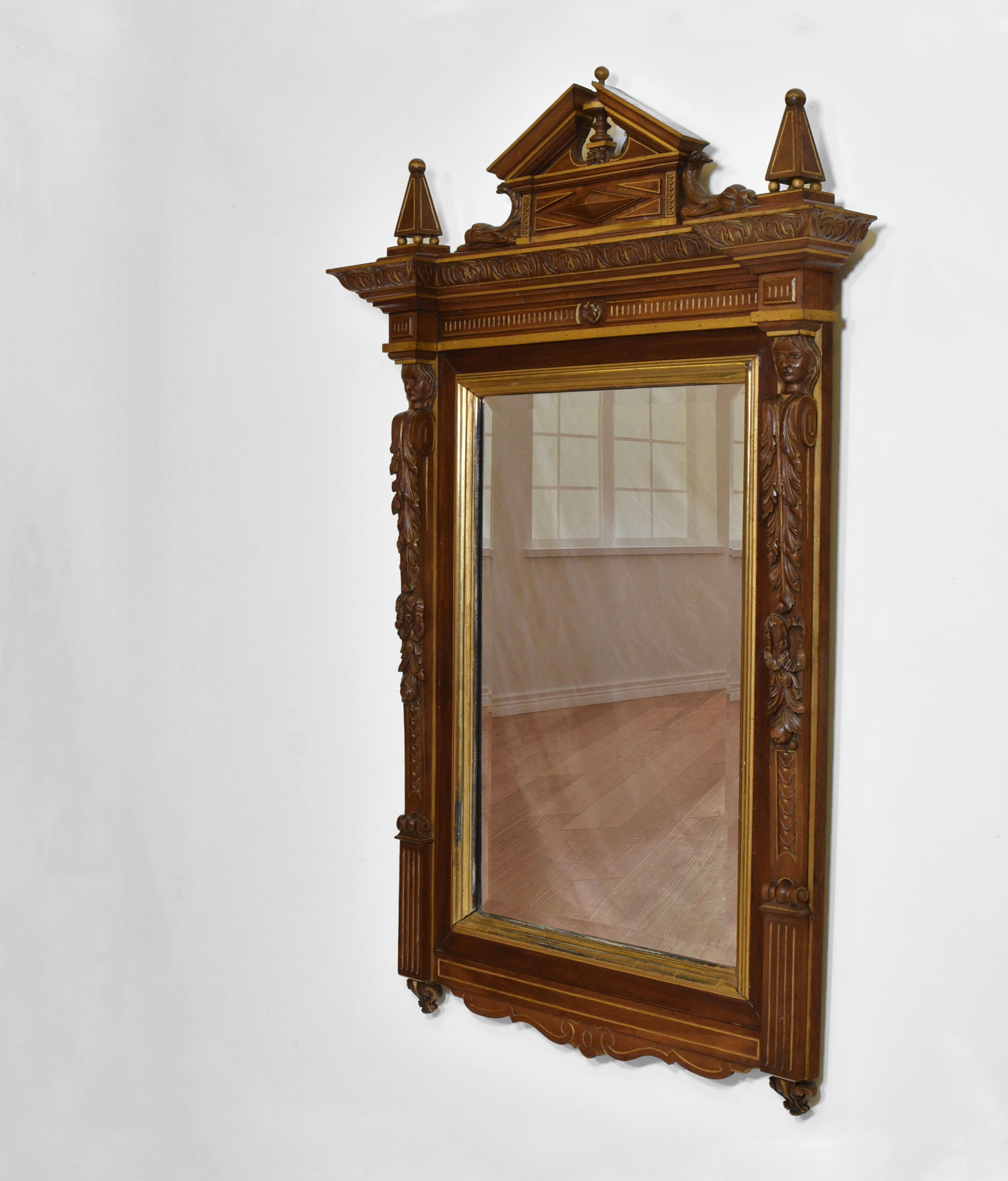 19th century Renaissance revival walnut and gilt wall mirror. Circa 1880.

The mirror has an architectural flavour. It is topped by a broken pediment with mythical carved animals, each banked by an obelisk. The column on either side of the glass