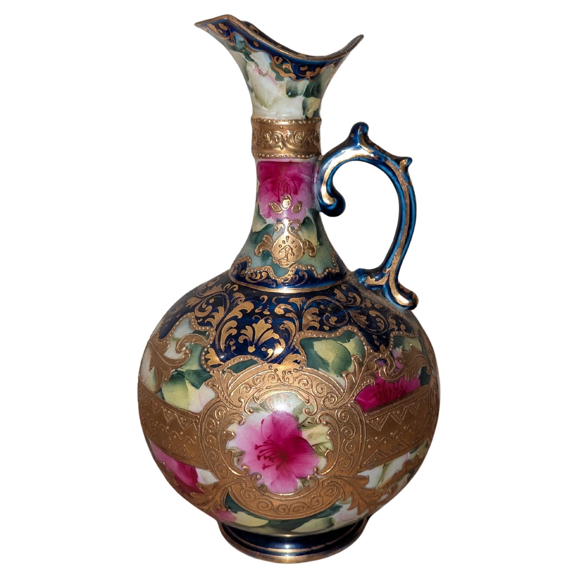 Cette exquise Aiguière Royale Nippone du 19ème siècle en or doré bleu cobalt et floral est une représentation magistrale de l'art et de l'élégance japonaise. La base de l'aiguière est d'un riche bleu cobalt, créant une toile saisissante pour ses