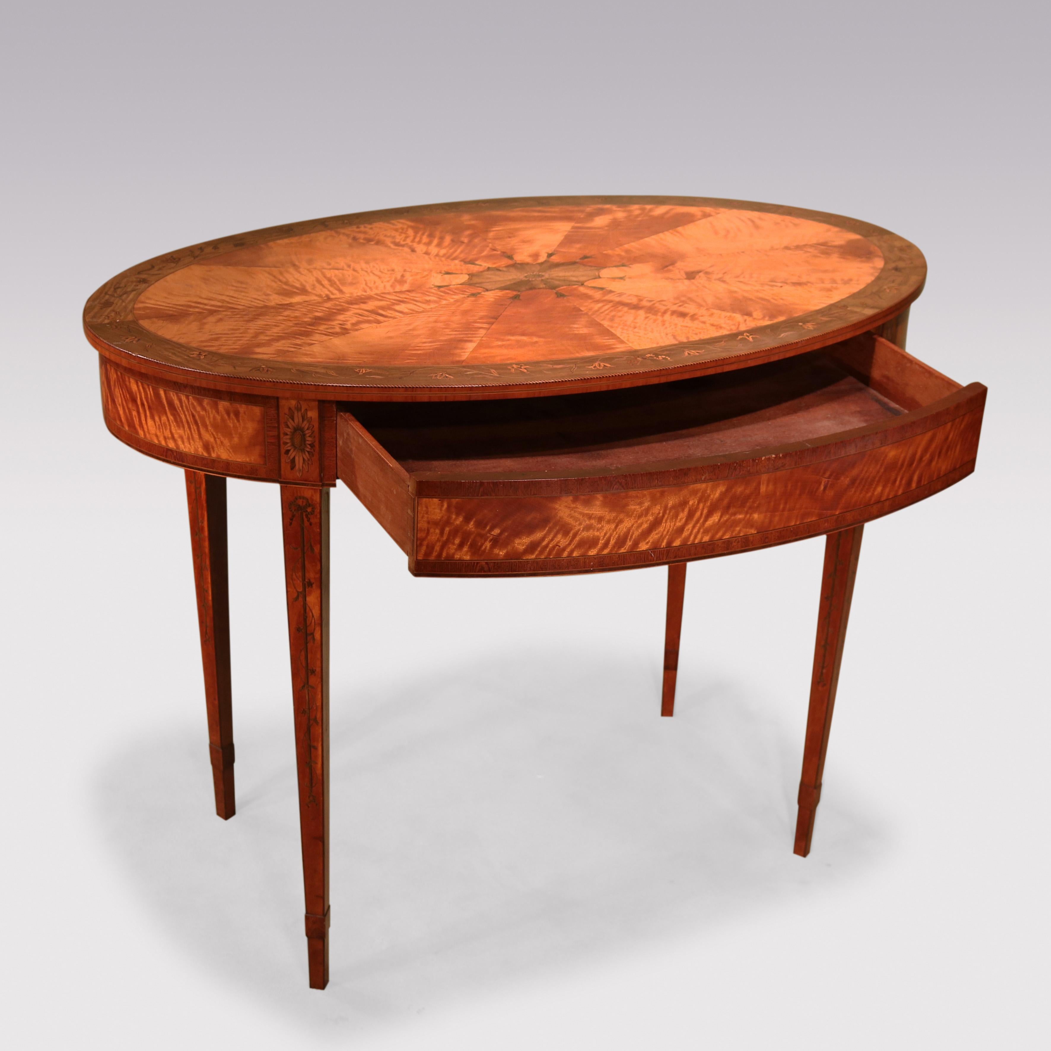 An attractive mid-19th Century satinwood Occasional Table in the 18th Century Sheraton style, having harewood crossbanding & floral inlaid segmented oval top above concealed drawer, supported on leaf scrolled & inlaid square tapering legs with leaf