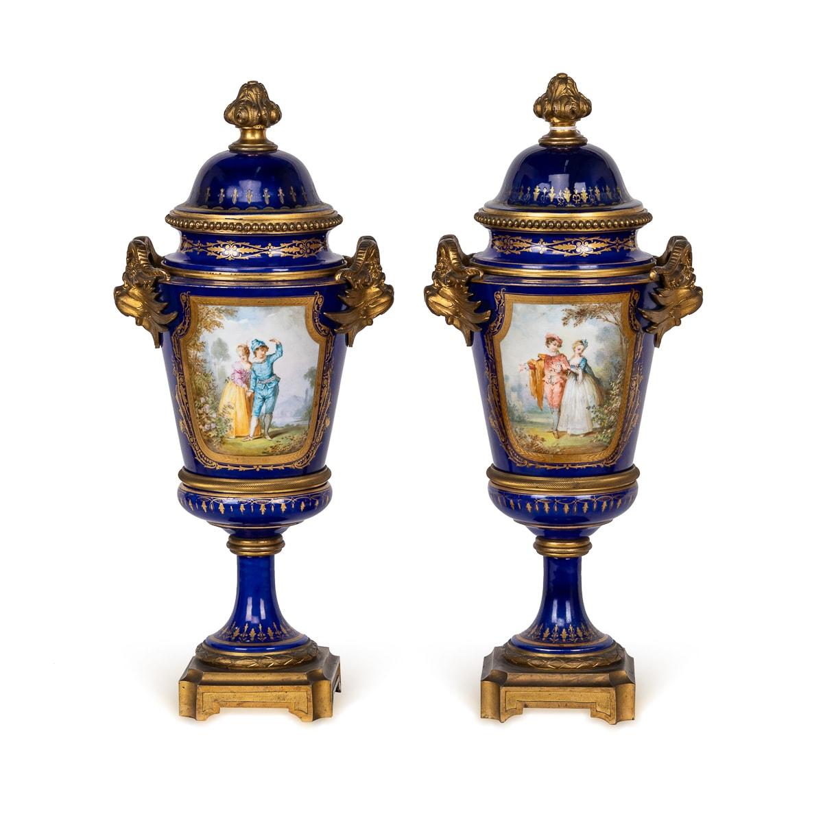 Antique 19th Century French Serres porcelain pair of lidded vases, exude elegance with their ornate ormolu mounts. Delicately adorned with graceful acanthus leaf handles, each vase features a lid crowned by a flower bulb finial, encircled by