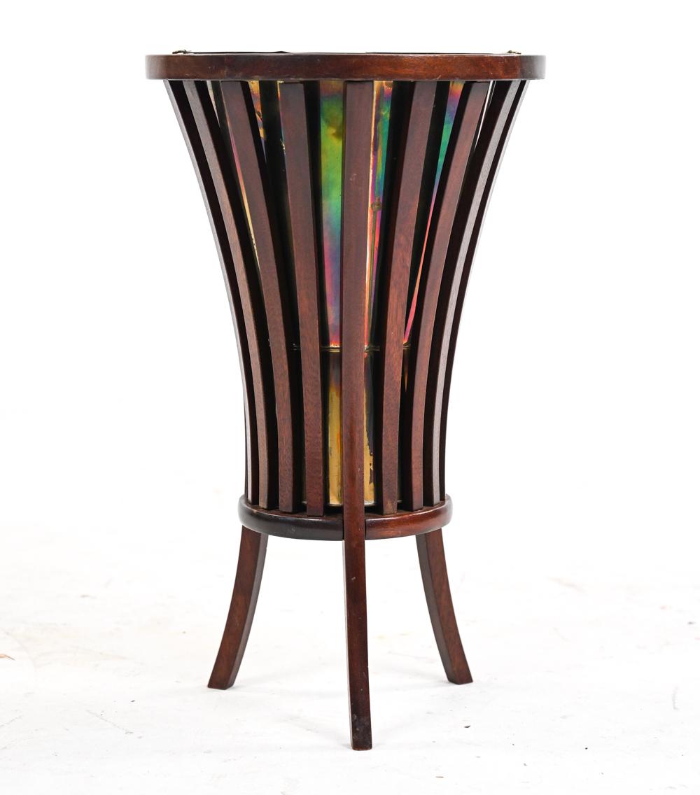 An unusual and rare plant stand or champagne cooler in artfully slatted and bent mahogany with a brass liner which has developed a lustrous rainbow patina over time.