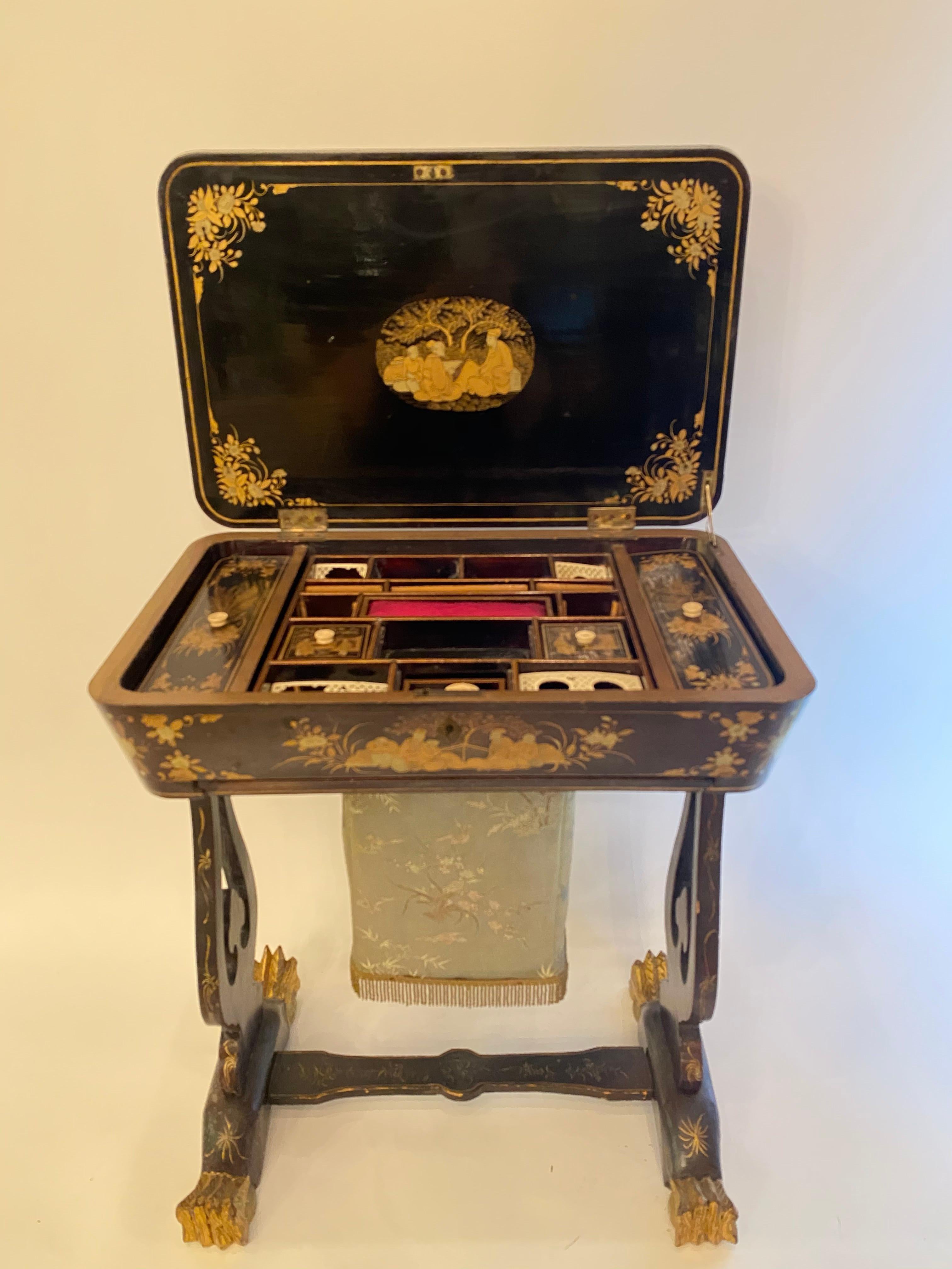 Ancienne petite table à couture en laque chinoise du 19ème siècle avec des scènes peintes à la main et de beaux pieds. Laque noire d'exportation dorée sur toute la table.