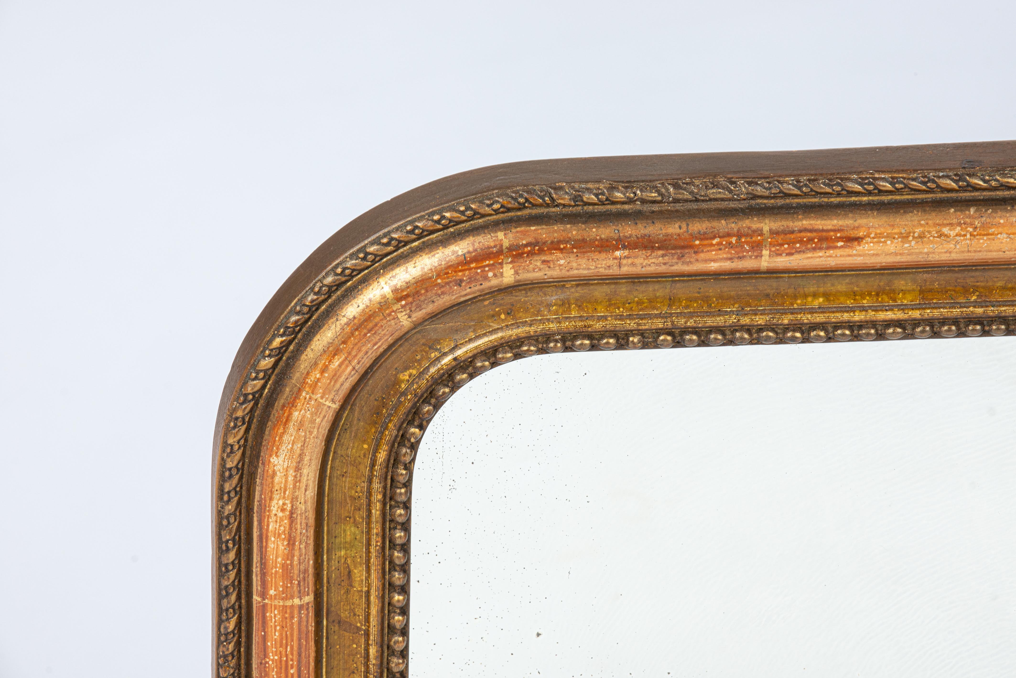Hier wird ein schöner kleiner antiker Spiegel angeboten, der in der zweiten Hälfte des 19. Jahrhunderts, um 1880, in Frankreich hergestellt wurde. Der Spiegelrahmen hat die für Louis Philippe-Spiegel typischen oberen abgerundeten Ecken. Eine zarte