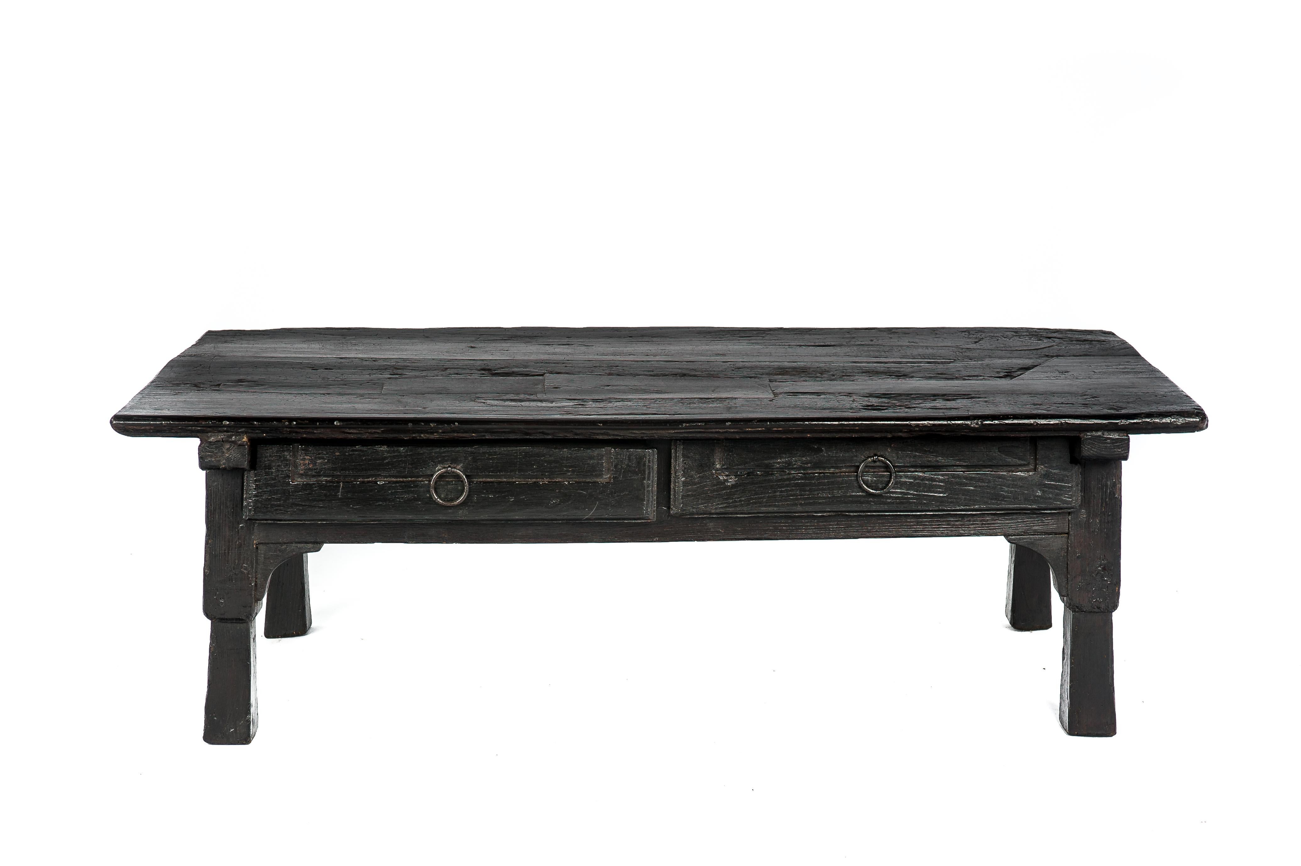 A beautiful dark coffee table that originates in Spain, circa 1840. 
The table is completely made in solid chestnut wood and shows the marks of many years of intensive use. The table has a thick top with many wood inserts and it is joined to the