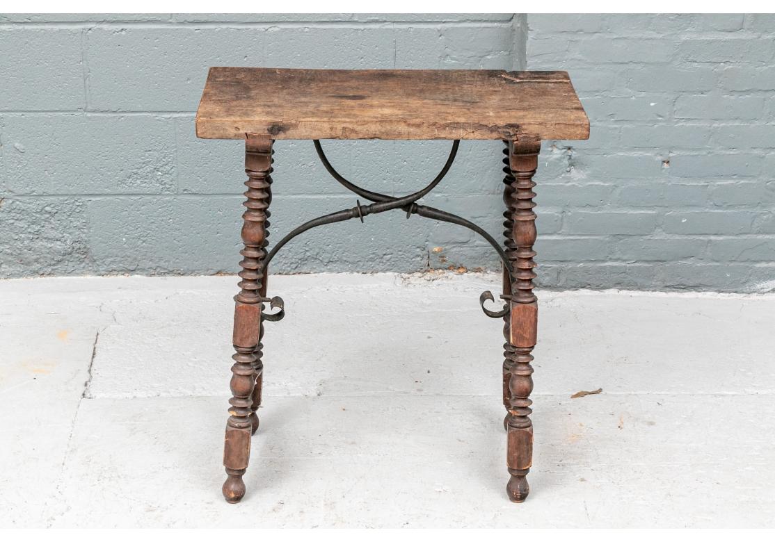 Side table having bobbin turned legs with a shaped iron trestle stretcher, small scalloped wooden side stretchers, hand cut joinery, peg construction and resting on elongated ball feet.
Dimensions: 25 1/2
