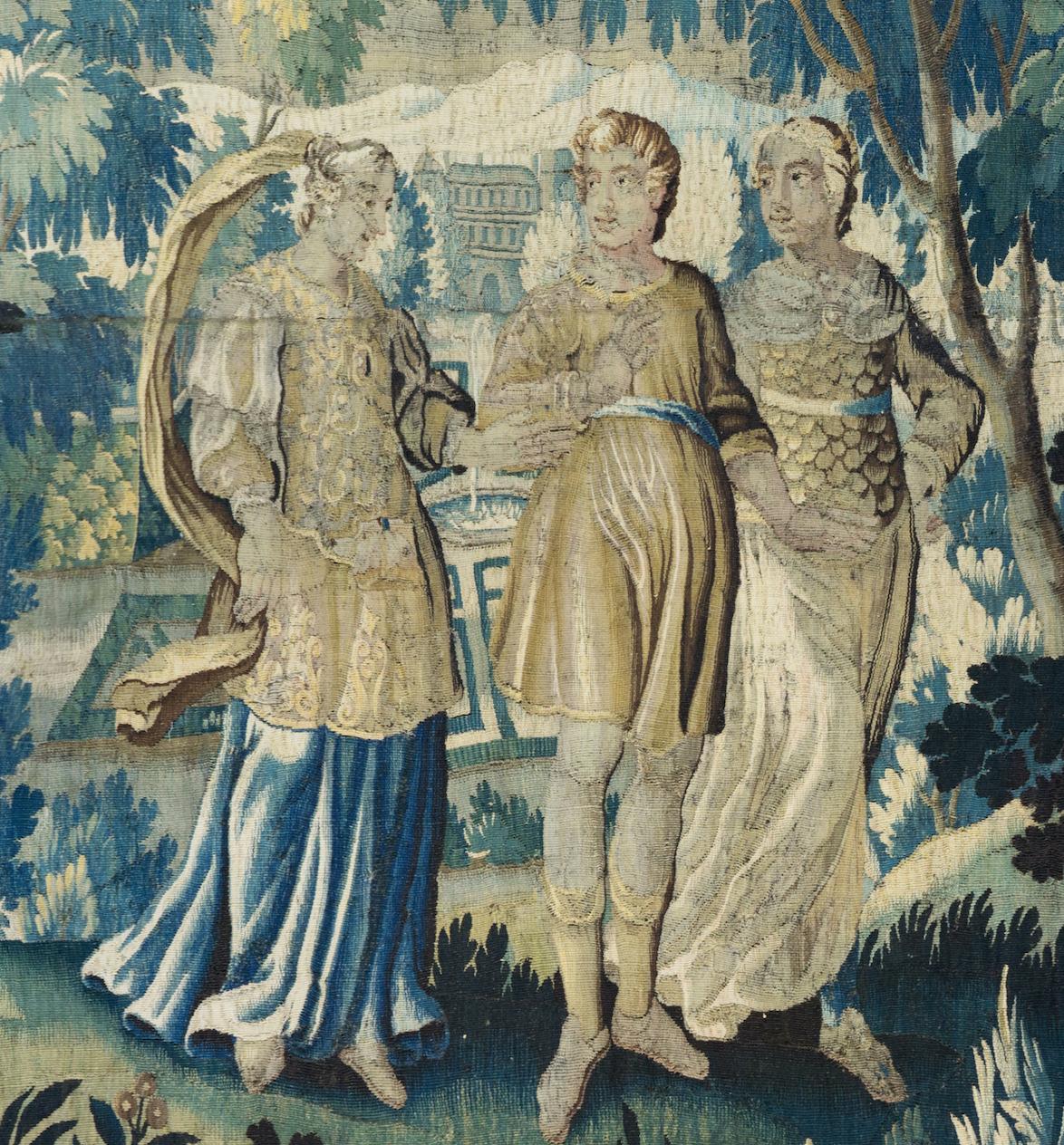 This is a lovely Antique 17th Century Square Green Floral Flemish Verdure tapestry depicting a nobleman out for a stroll with two noblewomen on a beautiful summer day in the countryside with lush trees and vegetation. We see the manor and its