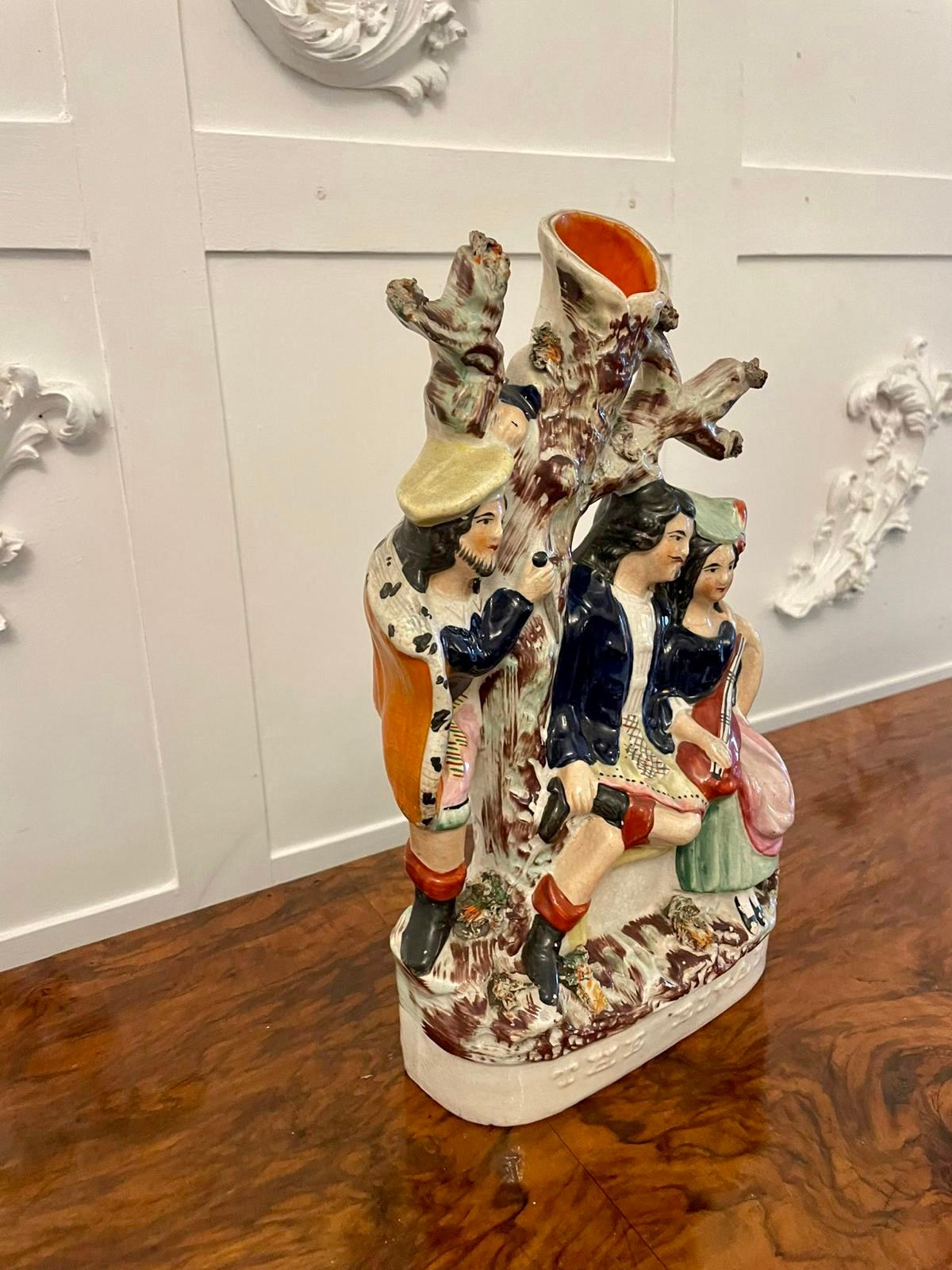 Antique 19th century Staffordshire flatback figure with a spill vase to the top depicting two lovers in period costume underneath a tree, the lady playing a mandolin and a further figure ‘The Rival’ watching behind the tree. 

A quaint figure with