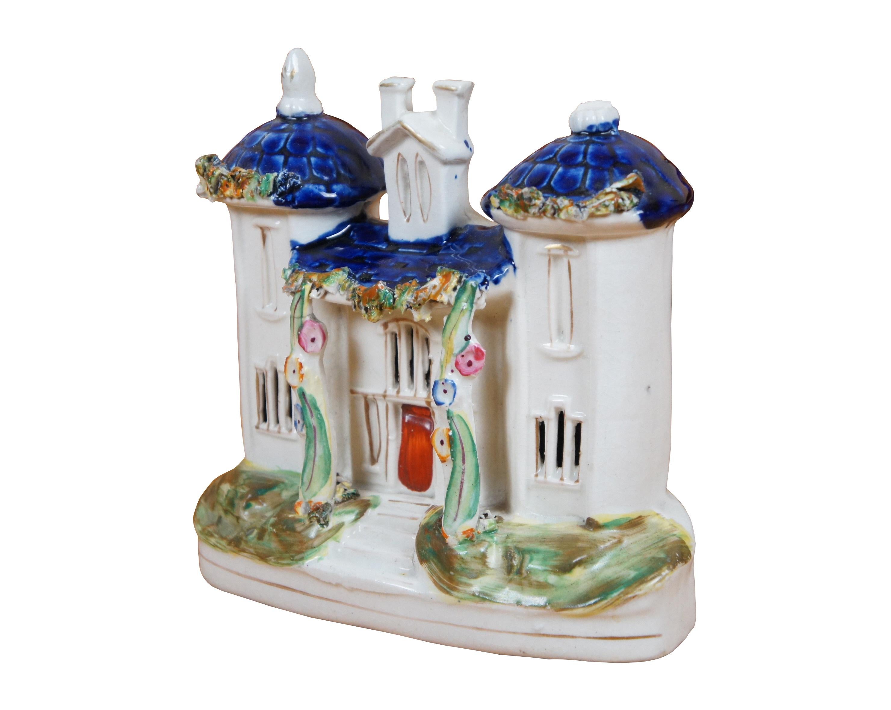 Antique 19th century English Staffordshire porcelain flatback figurine in the shape of a church / manor house / castle / pastille burner with three towers and blue roofs, front columns trimmed with flowering vines.

Dimensions:
7.25