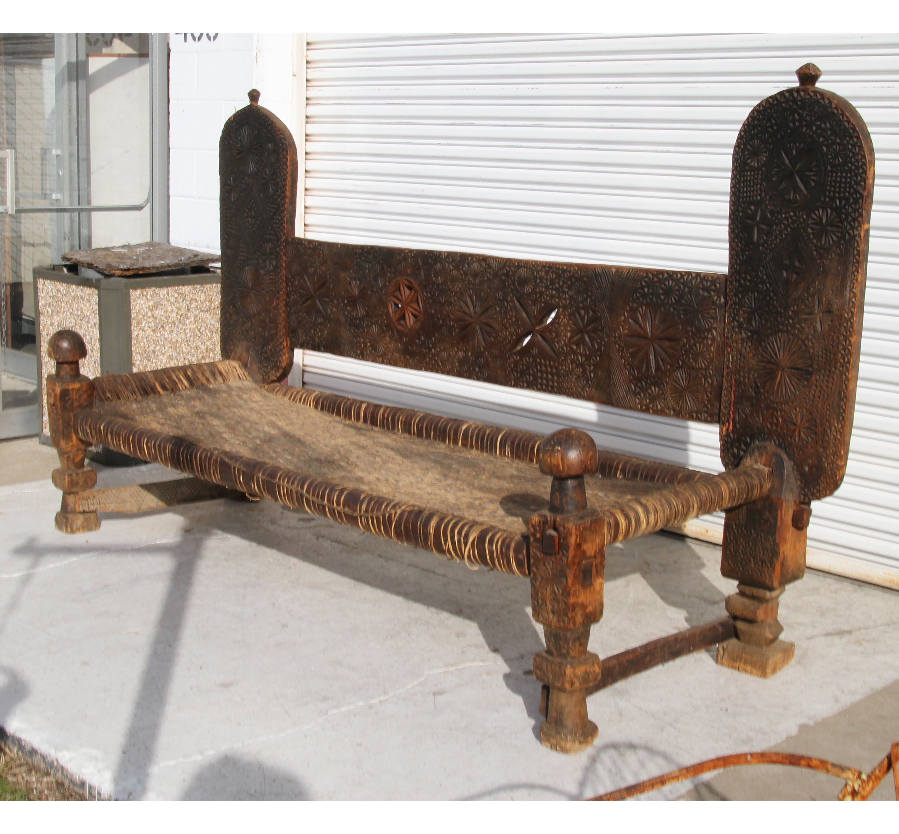 19th century Swat Valley bench with carved back in geometric patterns, large front legs with carved finials, and a woven seat. 
 
Measures: Width: 104”( headboard )
Length: 91” ( sitting area )
Depth: 36”.

  