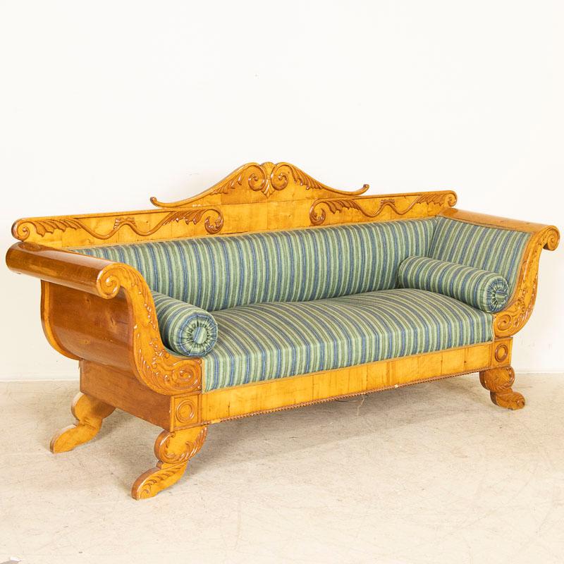 Drama and elegance combine in this lovely example of Swedish Biedermeier craftsmanship. This stunning antique sofa is made from polished yellow birch that seems to glow with life. Notice how the dramatic, large rolled arms are formed and curve