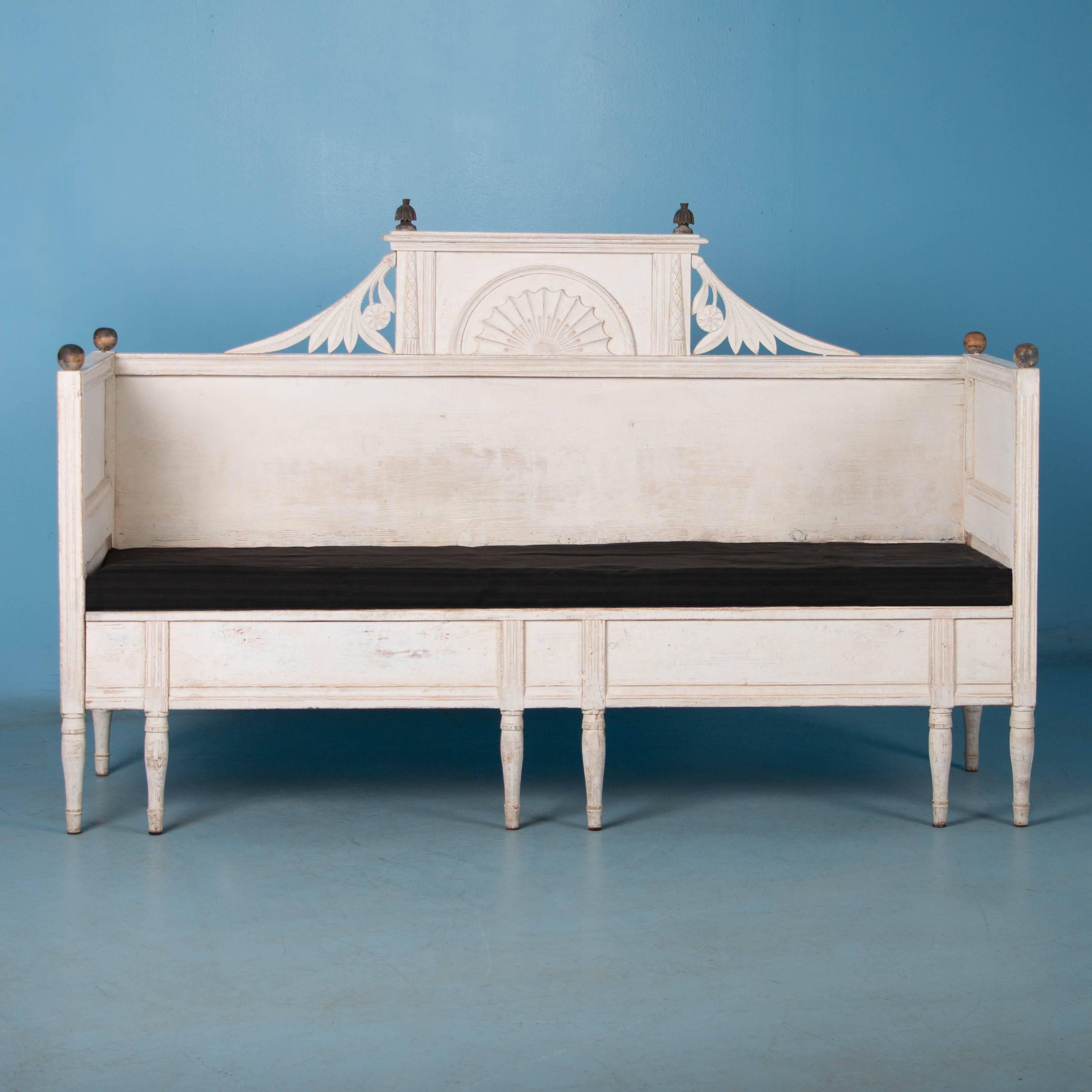  This lovely pine bench is a wonderful example of Swedish Gustavian country craftsmanship. The lightly distressed white paint with black finials and carved details add to its allure. The seat opens to reveal  a storage space below.  This style of