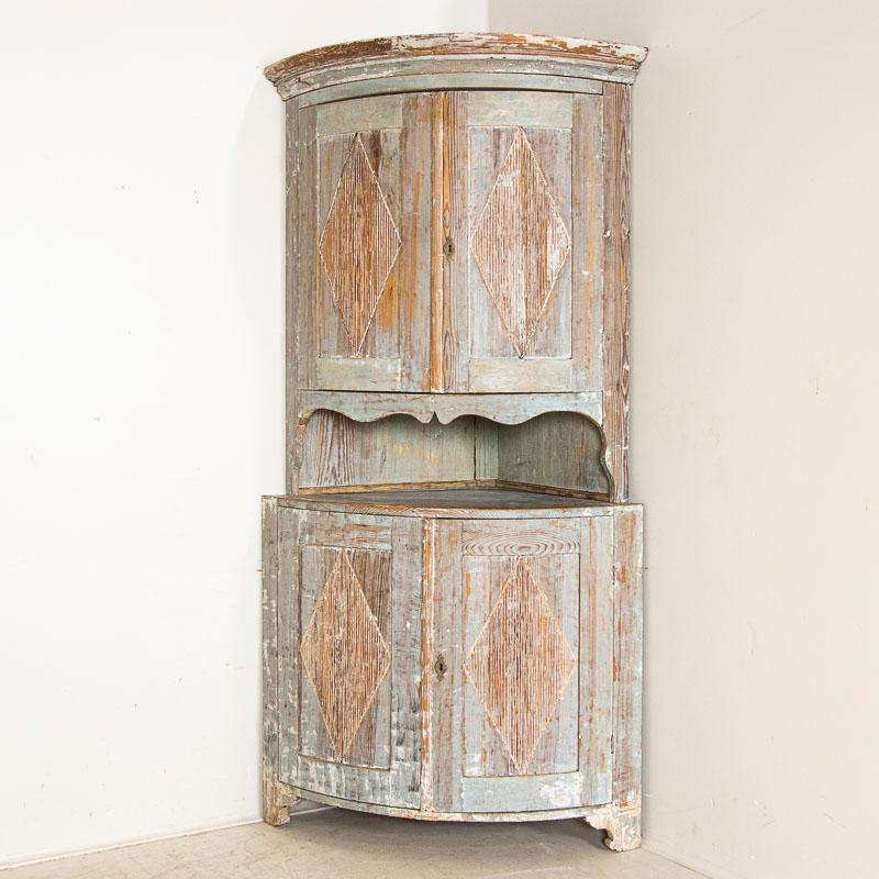 This antique Gustavian bowed front corner cabinet is in remarkable original condition. Note the attractive, aged gray painted finish that reveals layers of earlier paint as you see traces of black, white, and soft blue, worn away through generations