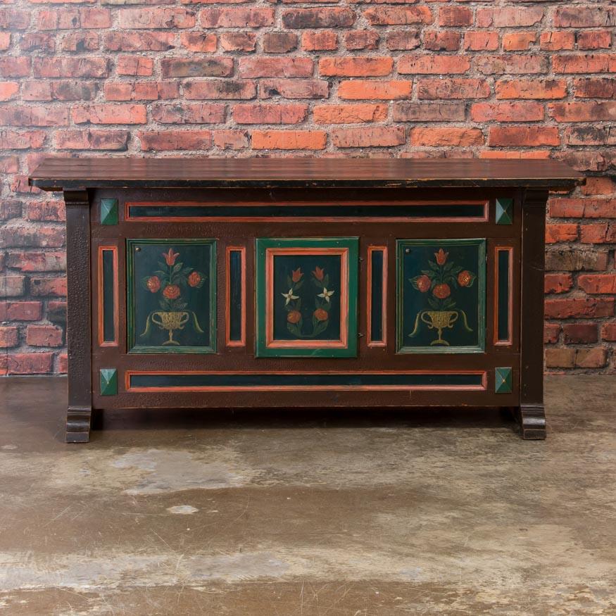 The delightful Folk Art painted front and side panels are a Traditional Design in country furniture from this era, and gives this small sideboard a whimsical cottage feel. Two of the molded doors on the cabinet open to a large storage space inside.