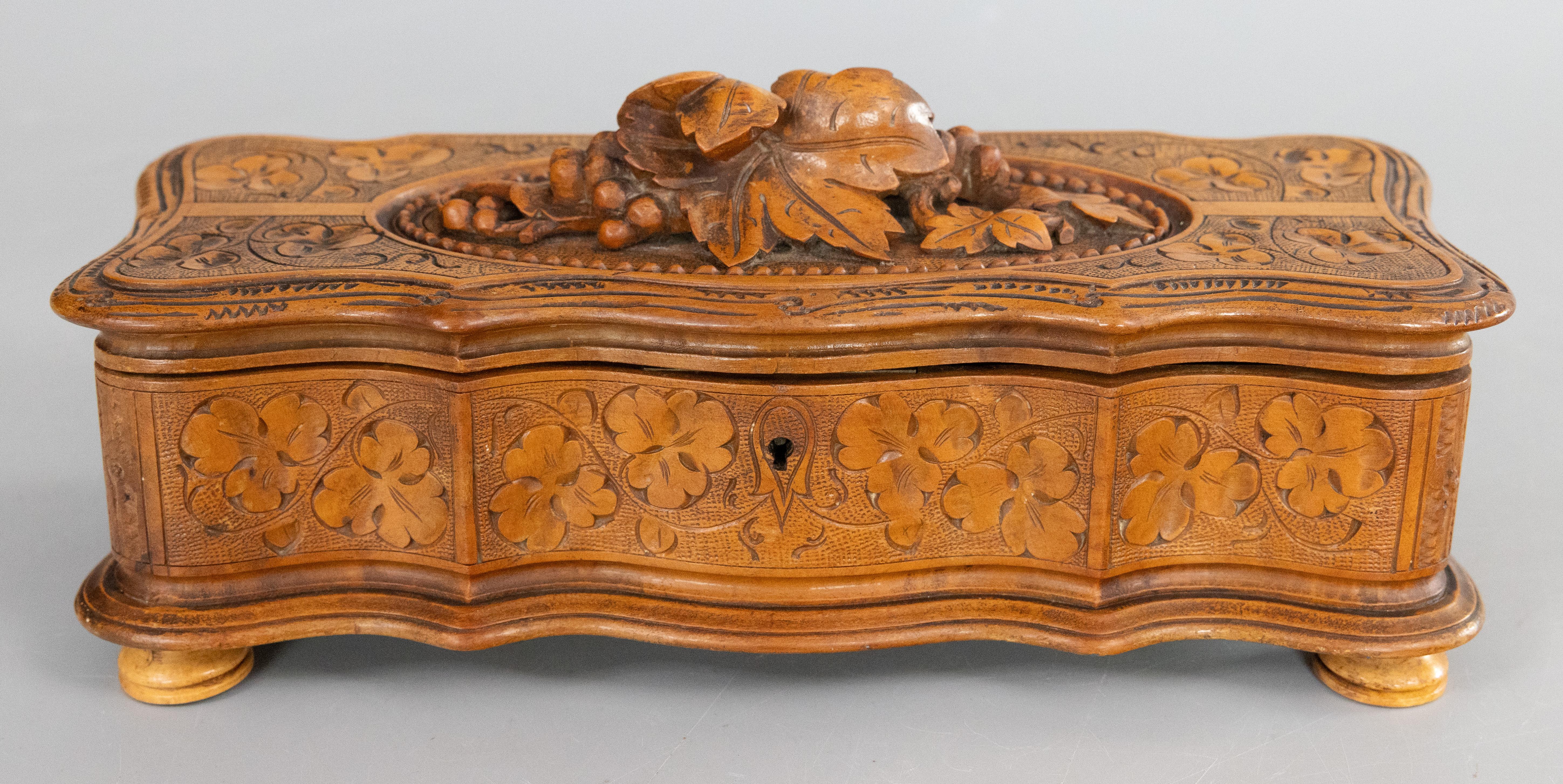 A superb antique Swiss Black Forest hand carved walnut footed glove box or jewelry box with velvet lined interior and original working lock and key, circa 1870. This fine box has a lovely serpentine shape with hand bevelled edge, raised on hand