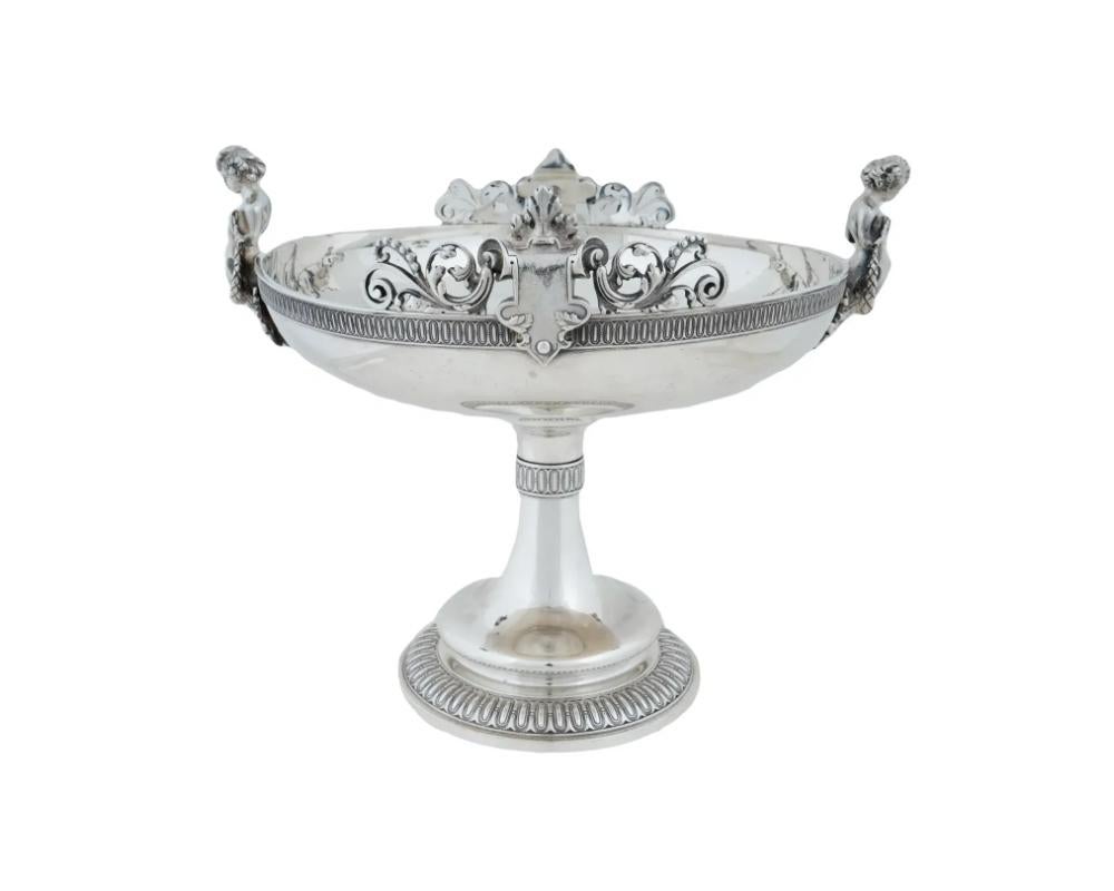 An exceptional quality antique Tiffany and Co. sterling silver centerpiece constructed of numerous castings assembled together. The wide round bowl is flanked by two figural handles and bears two decorative cartouches with scrolled openwork foliage