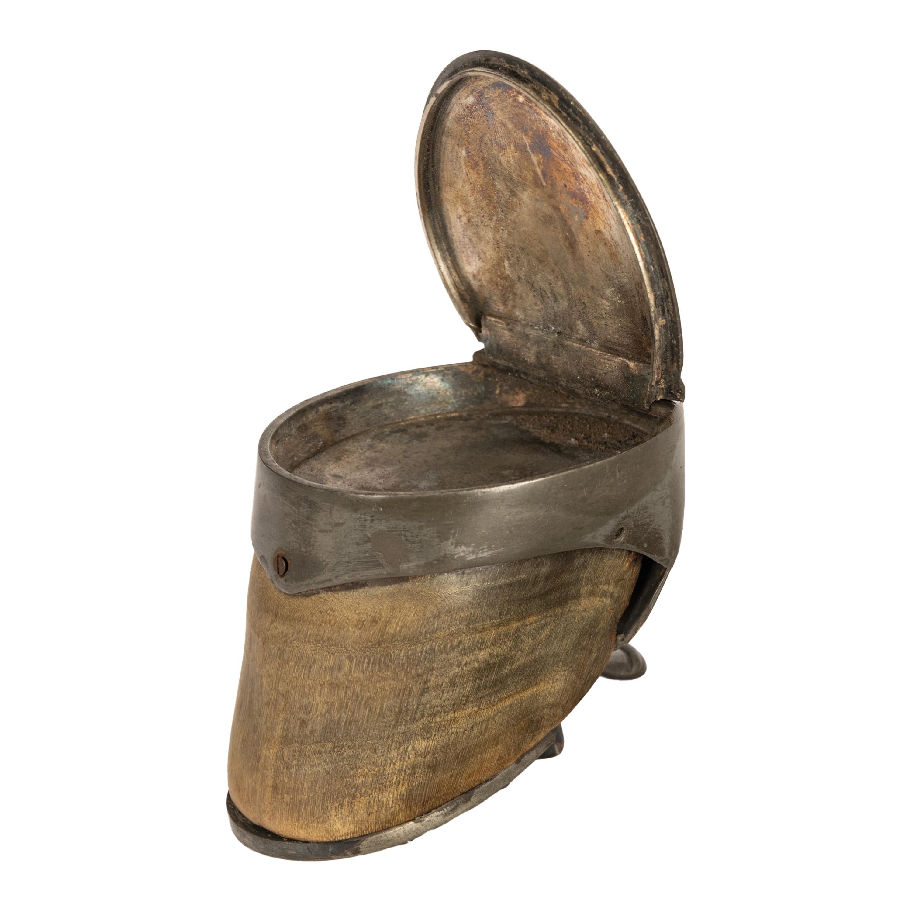 Une tabatière victorienne inhabituelle en sabot de cheval et en étain, datant du milieu du 19e siècle, vers 1860.
La tabatière a un couvercle à charnière avec une décoration florale gravée et un fleuron enroulé pour ouvrir la boîte, la base avec une