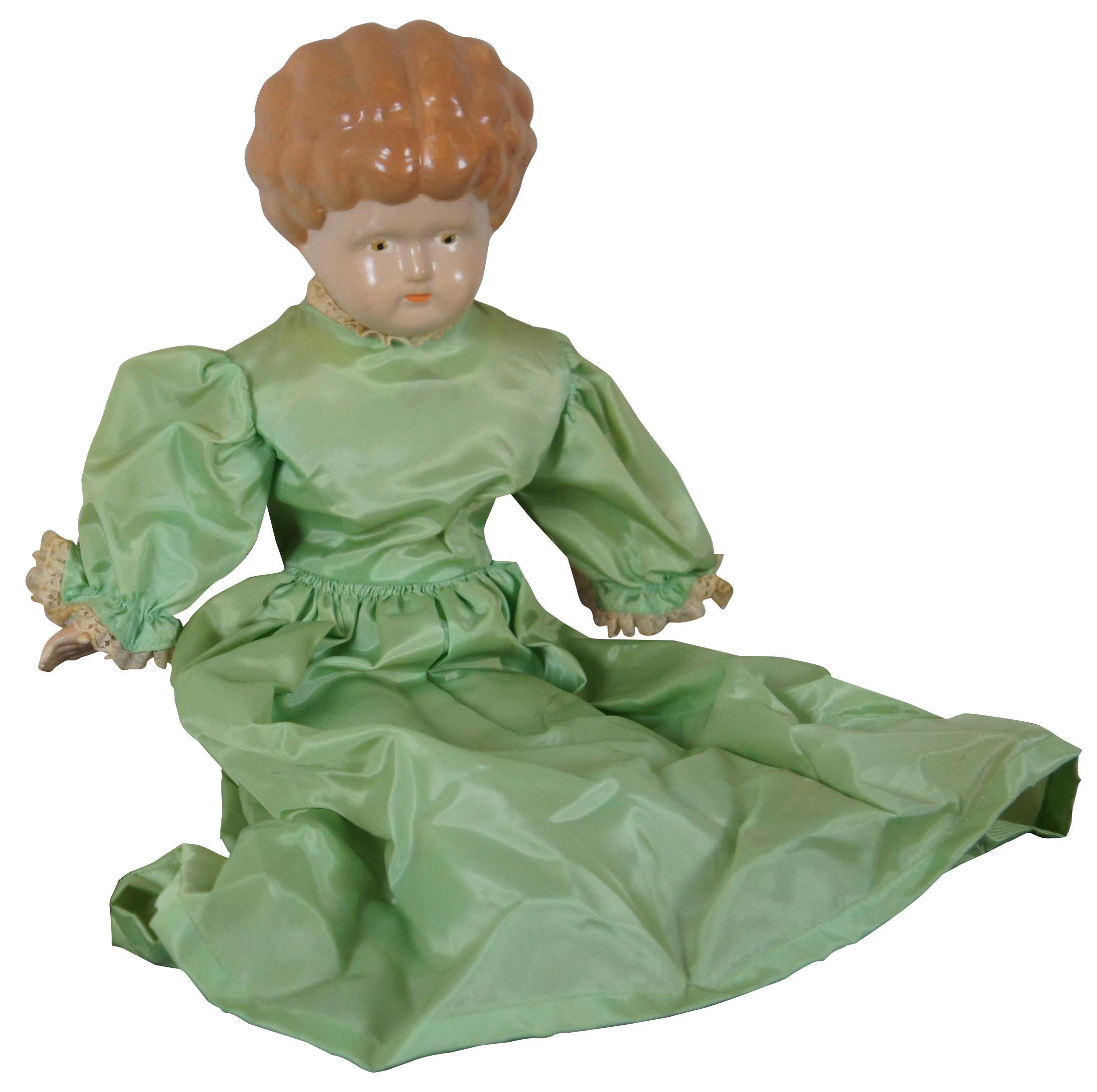 Poupée allemande en porcelaine, datant du milieu du XIXe siècle, avec buste, pieds et mains en porcelaine peinte, corps en tissu et robe verte. Mesures : 18