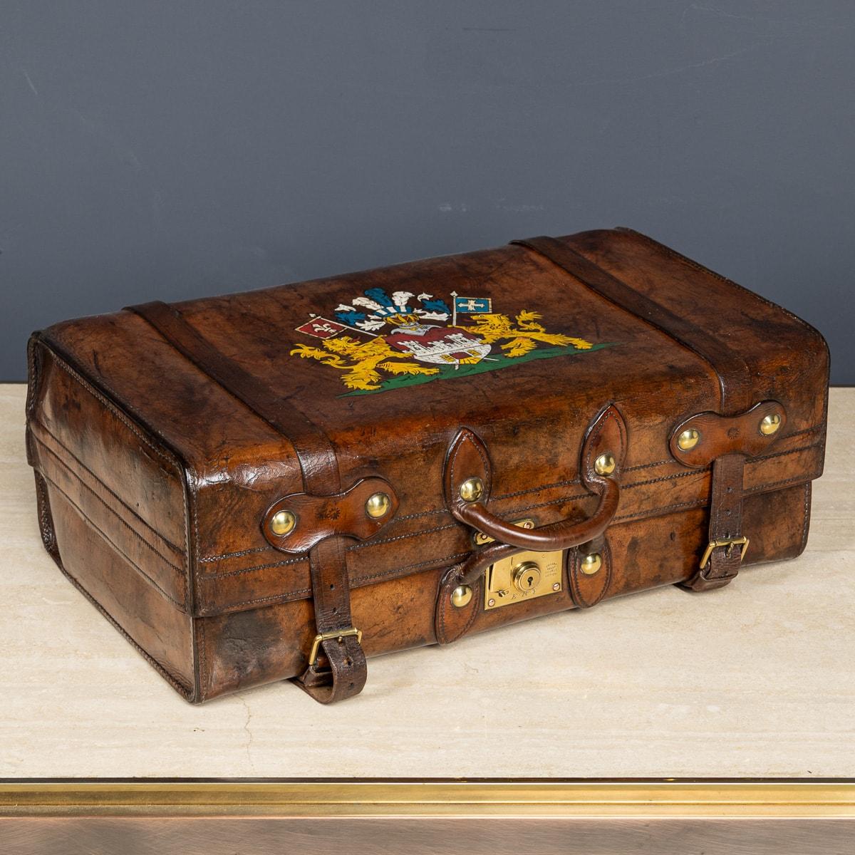 Ancienne valise victorienne en cuir du milieu du 19e siècle avec un écusson familial peint. La valise est très bien conservée et comporte la doublure en coton d'origine, un porte-documents et des housses de protection avec des sangles en cuir. La