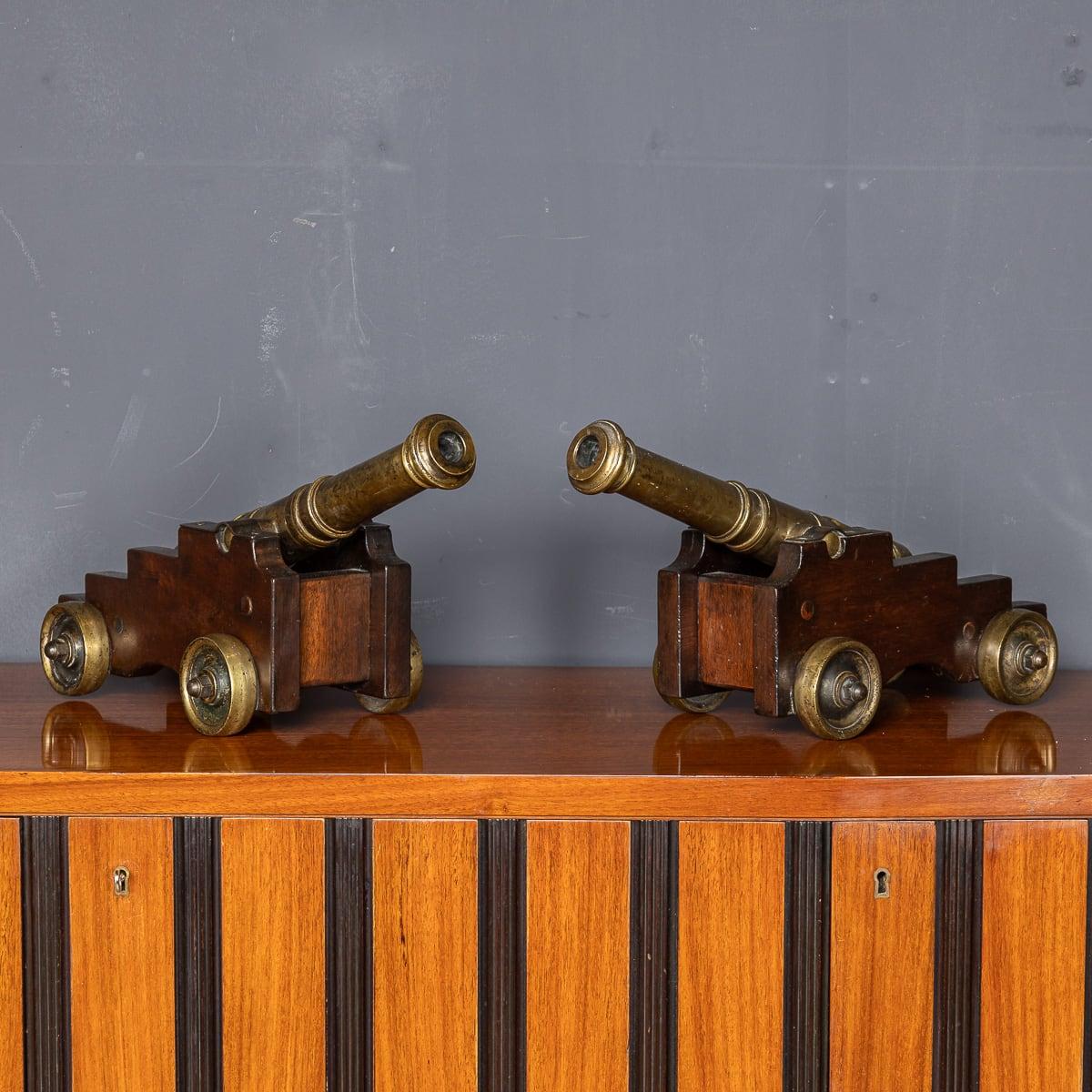 Antique 19th Century Victorian pair of brass signal cannons, mounted on brass-wheeled wooden bases. Each features a lighting fuse hole on top and a decorative stamped plaque depicting a man on horseback along the cannon shaft. Ideal as distinctive