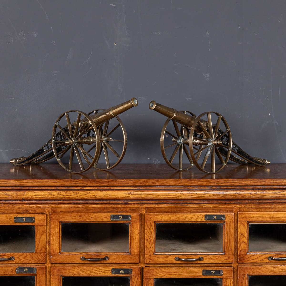 Antique 19th Century Victorian pair of cast brass desk cannons. Mounted on large spoked wheels, these canons feature a long barrel and chassis. A wonderful decorative item for any desk, these pieces make for fantastic conversation starters, suitable