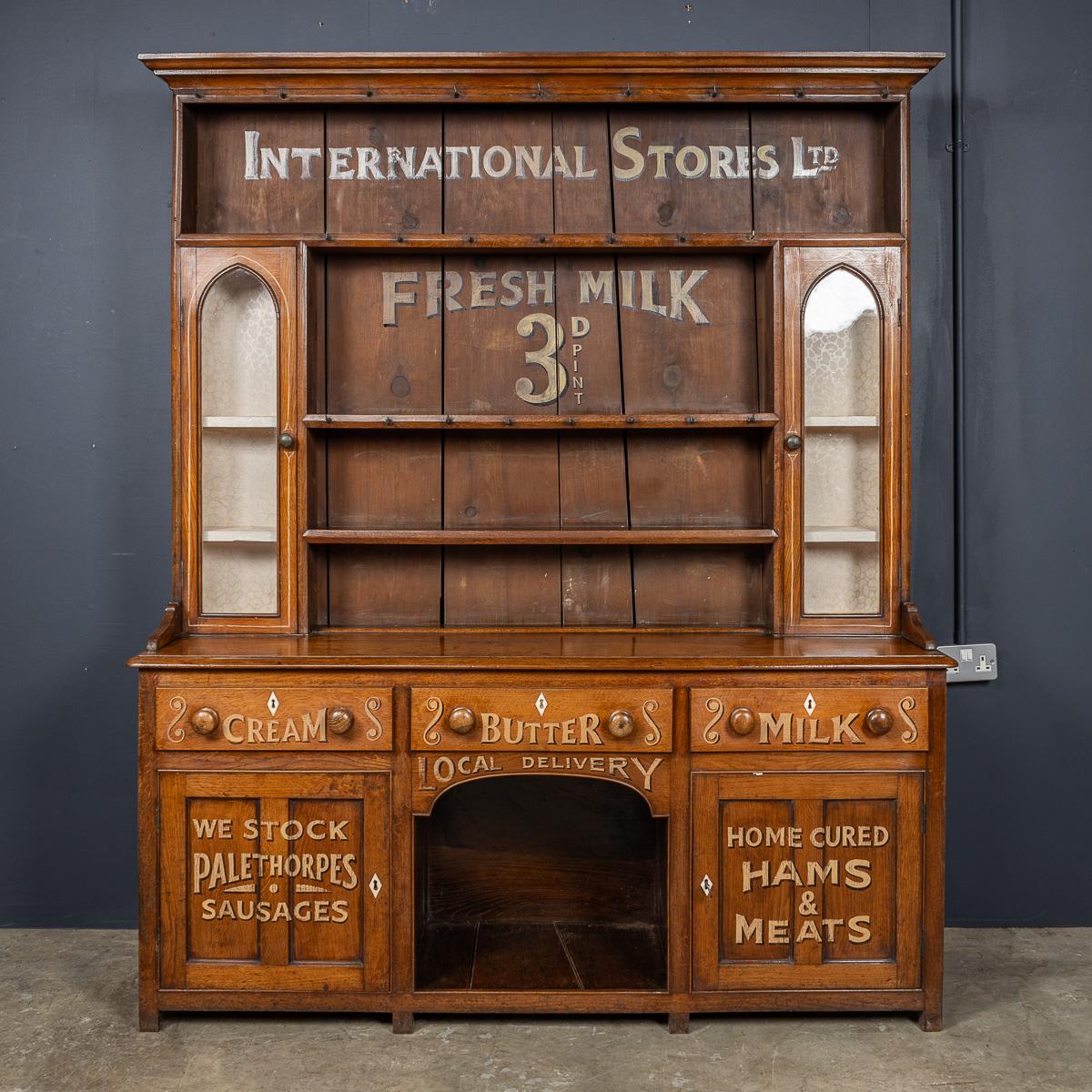 Antique 19th Century Victorian oak dresser, dating to the 1880, featuring two glass-fronted cupboards, drawers, and enclosed cupboards beneath. It was later painted for use in a local farm dairy trading for International Stores Ltd.

CONDITION
In