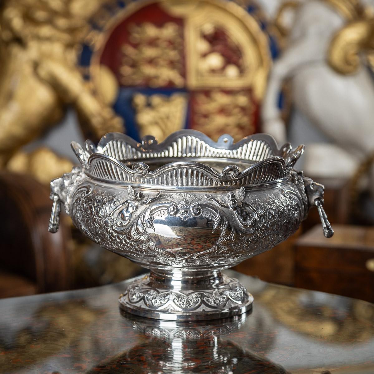 Antique late-19th Century Victorian solid silver armada bowl, the body is intricately adorned with elaborate chasing and embossing, showcasing a pristine floral decoration. On each side, finely crafted projecting angels flank an empty cartouche,