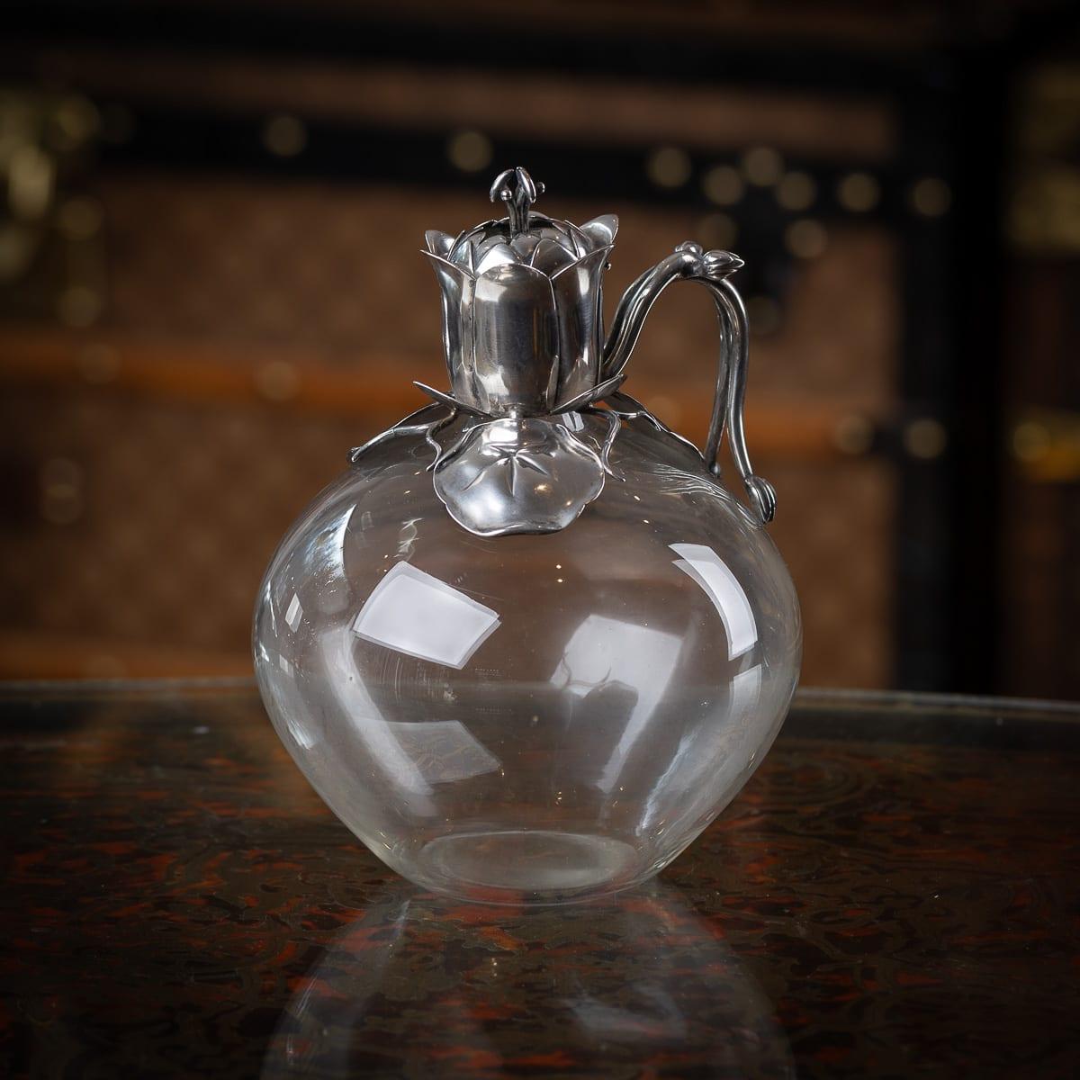 Antique 19th Century Victorian solid silver & clear glass claret jug. Modelled in a organic style with floral decorative spout and handle terminating with two flower buds. The body of the claret jug is of a spherical shape. Such novelty claret