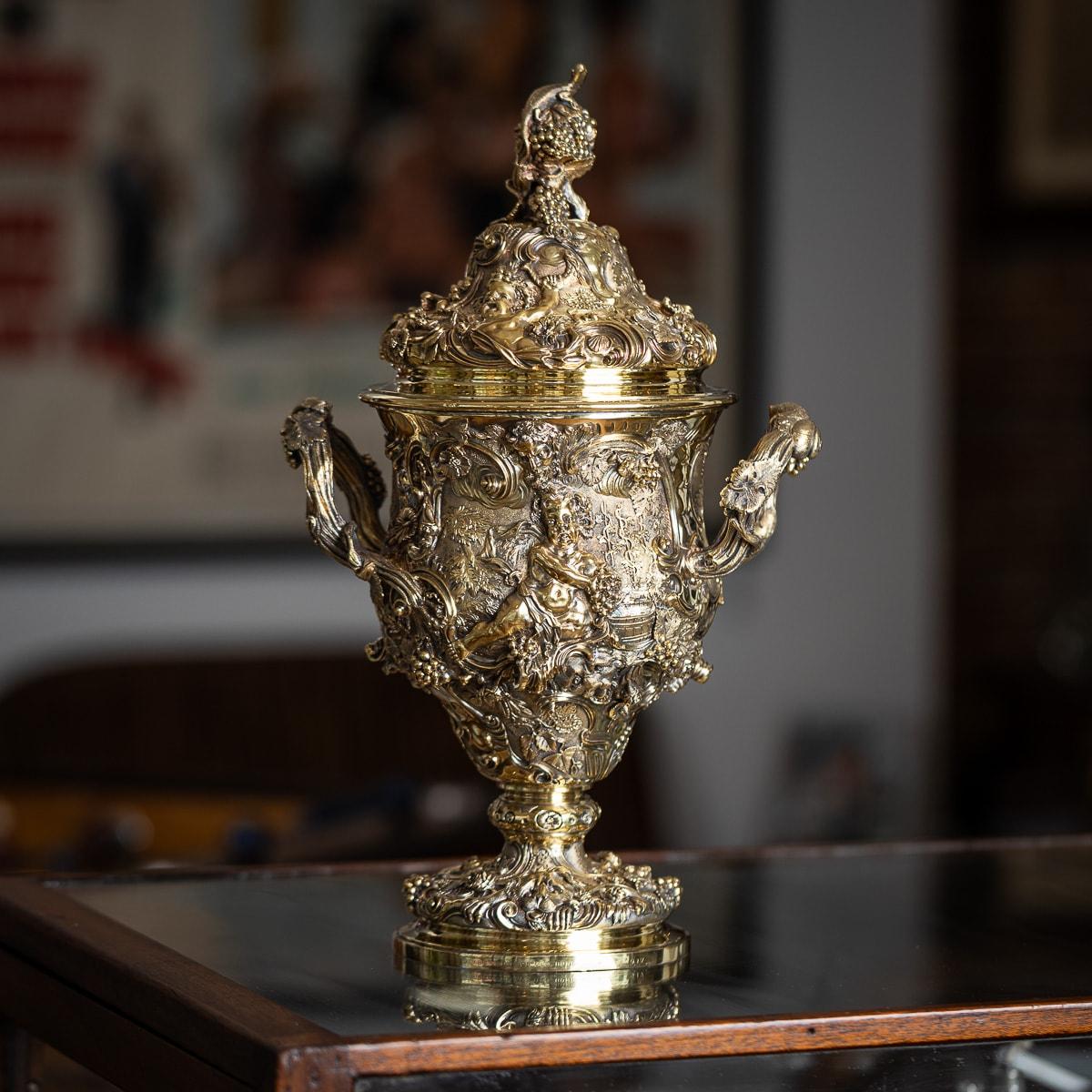 Die antike viktorianische Tasse aus massivem Silber mit zwei Henkeln und Deckel aus dem 19. Jahrhundert ist ein bemerkenswertes Stück, reich vergoldet und exquisit gegossen und punziert. Es zeigt lärmende Putten, Löwen, Weinreben, Insekten,