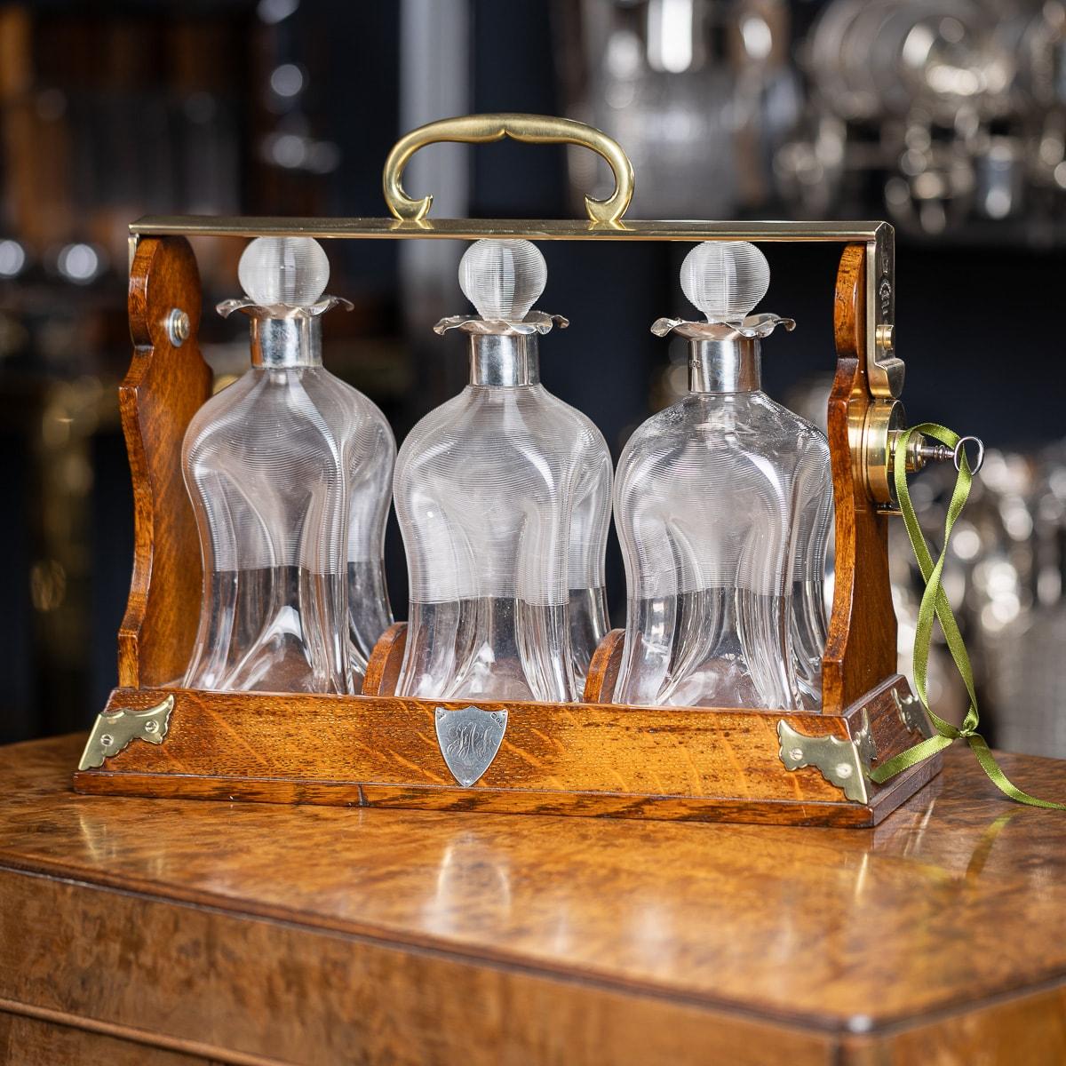 Antique 19th Century Victorian three-bottle tantalus features brass detailing and a locking mechanism stamped with 