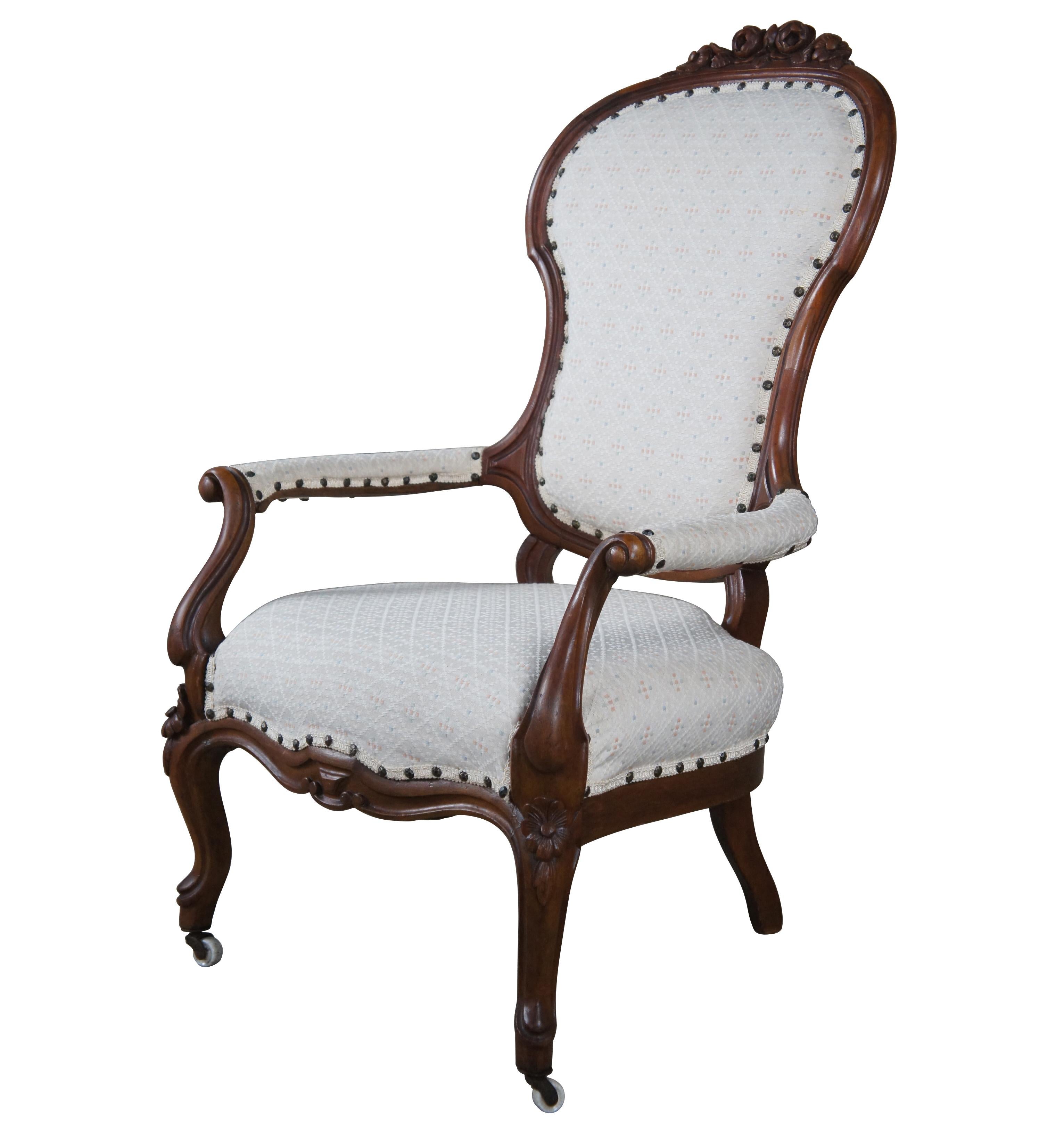 A lovely Victorian era spoon back arm chair. Made from walnut with flared and scrolled upholstered arms. Features daisy, rose and leaf carvings. The chair is raised over cabriole legs along the front with casters. Upholstery is white with a diamond