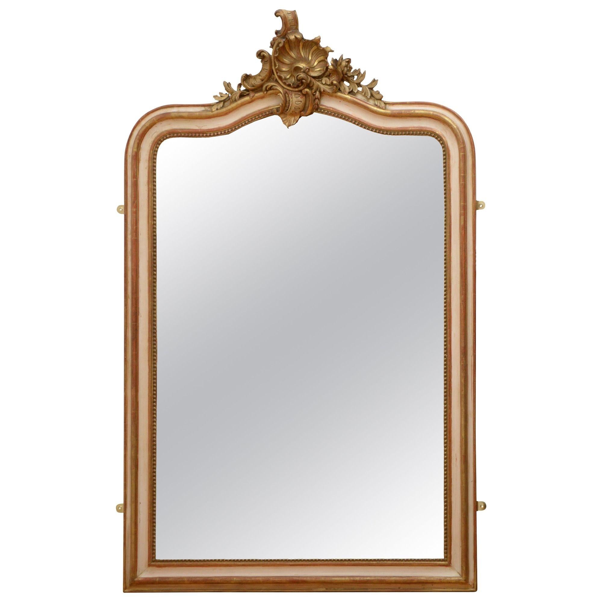K0467 beau miroir mural français, crème et feuille d'or, avec verre biseauté d'origine avec un peu de rouille dans un cadre perlé et façonné avec crête centrale de coquille et de fleur sur le dessus. Ce miroir antique a conservé son verre d'origine,