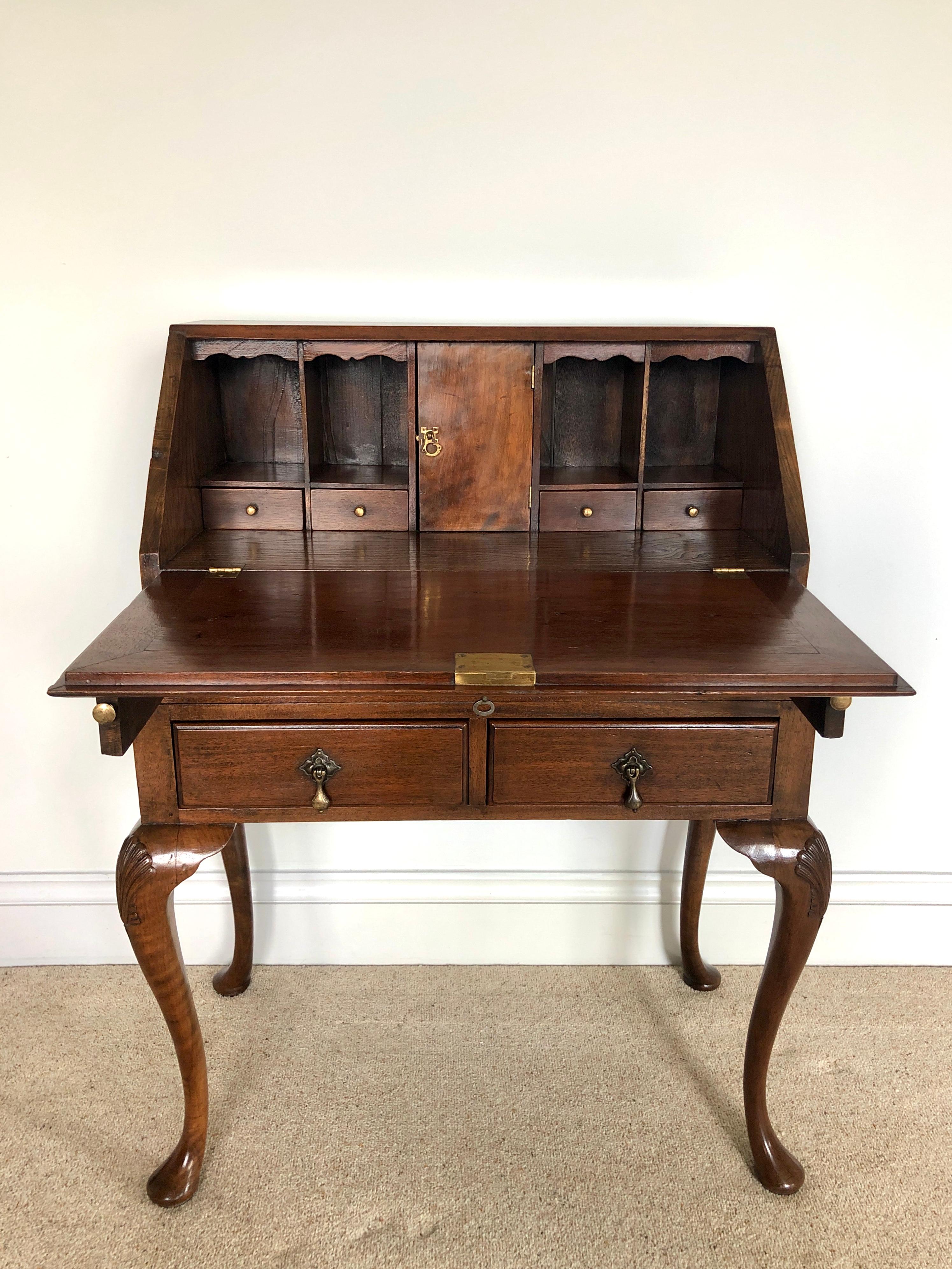 Antique walnut bureau

Antique walnut bureau having a solid walnut fall opening to reveal a fitted interior consisting of two drawers, pigeon holes and a door to the centre. One long and two short drawers beneath with original brass drop handles