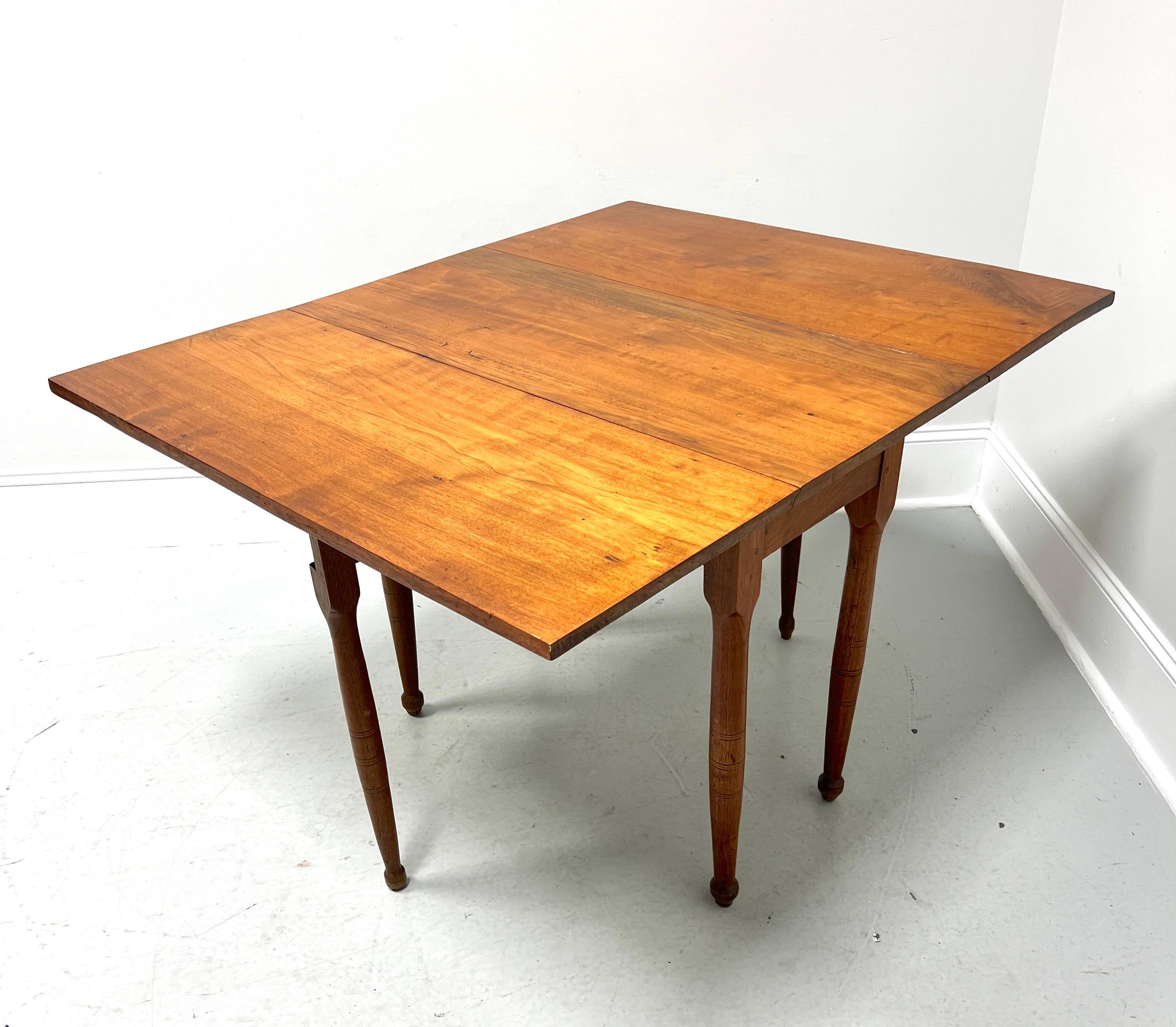 An antique 19th Century Colonial style gateleg drop-leaf dining table, unbranded. Solid walnut, a center apron, and six round tapered straight legs, two being gateleg that swing out to support the drop leaves when raised. Made in the USA.

Measures: