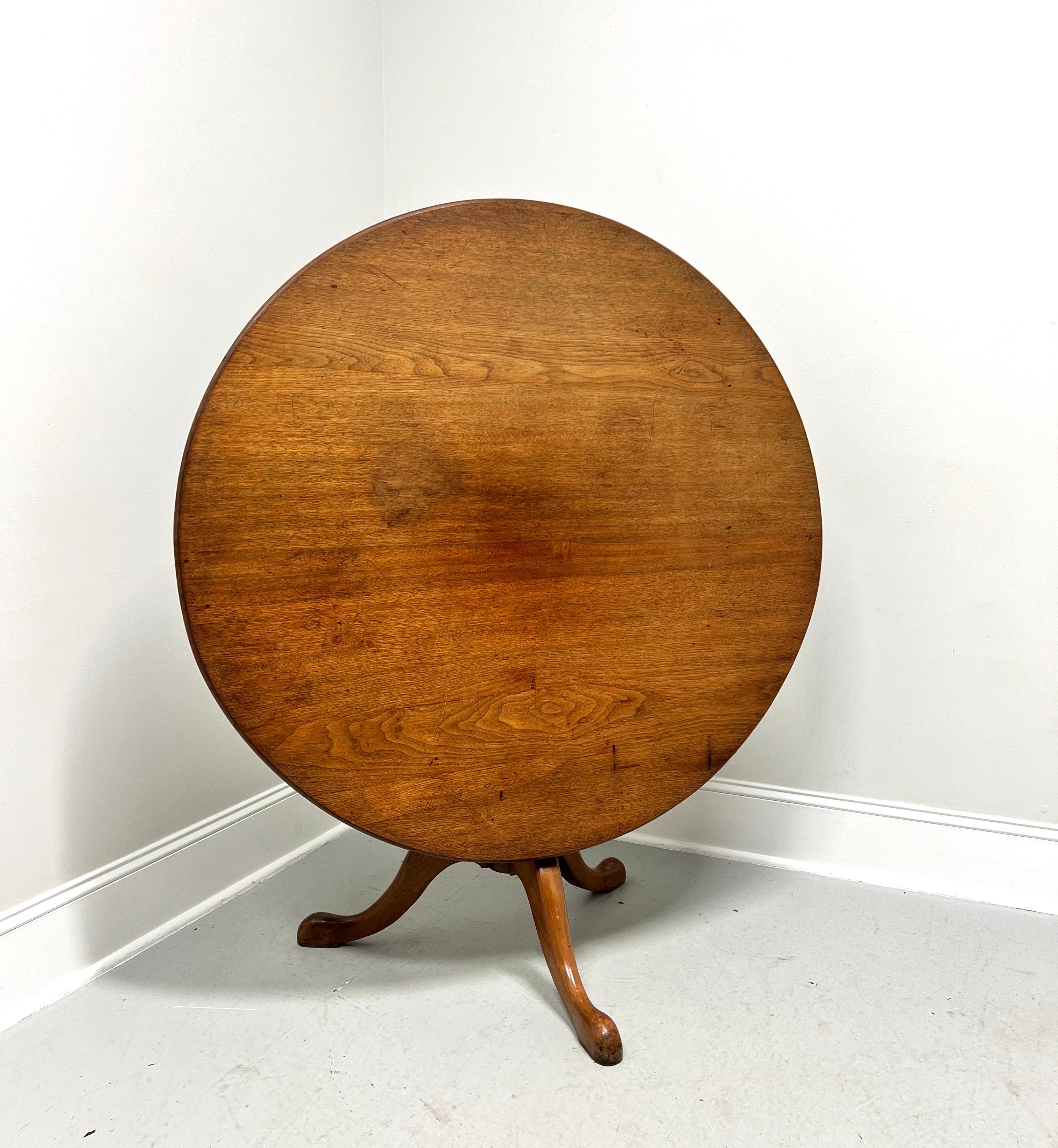 An antique 19th Century Queen Anne style tilt-top dining table, unbranded. Solid walnut, round top with bevel edge, tilts up on pivots, walnut slide latch, turned pedestal, three legs, and pad feet. Made in the USA.

Measures:  Table Top Down: 47.5w