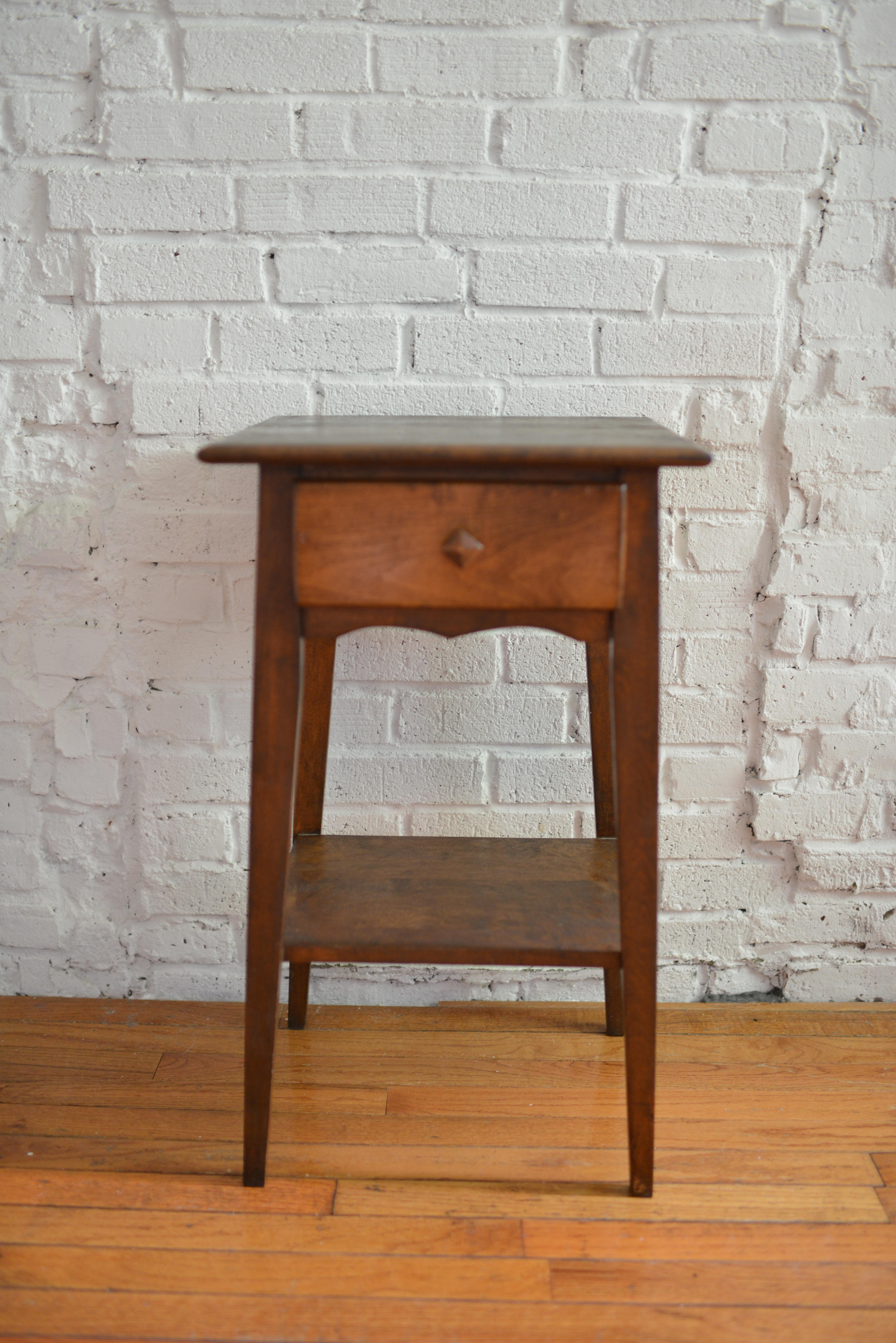 Adorable 19th century walnut side table / end table. This Hepplewhite style table has tapered legs, a single drawer with a shapely apron front and a diamond-shaped wood knob. The top and drawer face feature pretty molded detailing. The square-ish