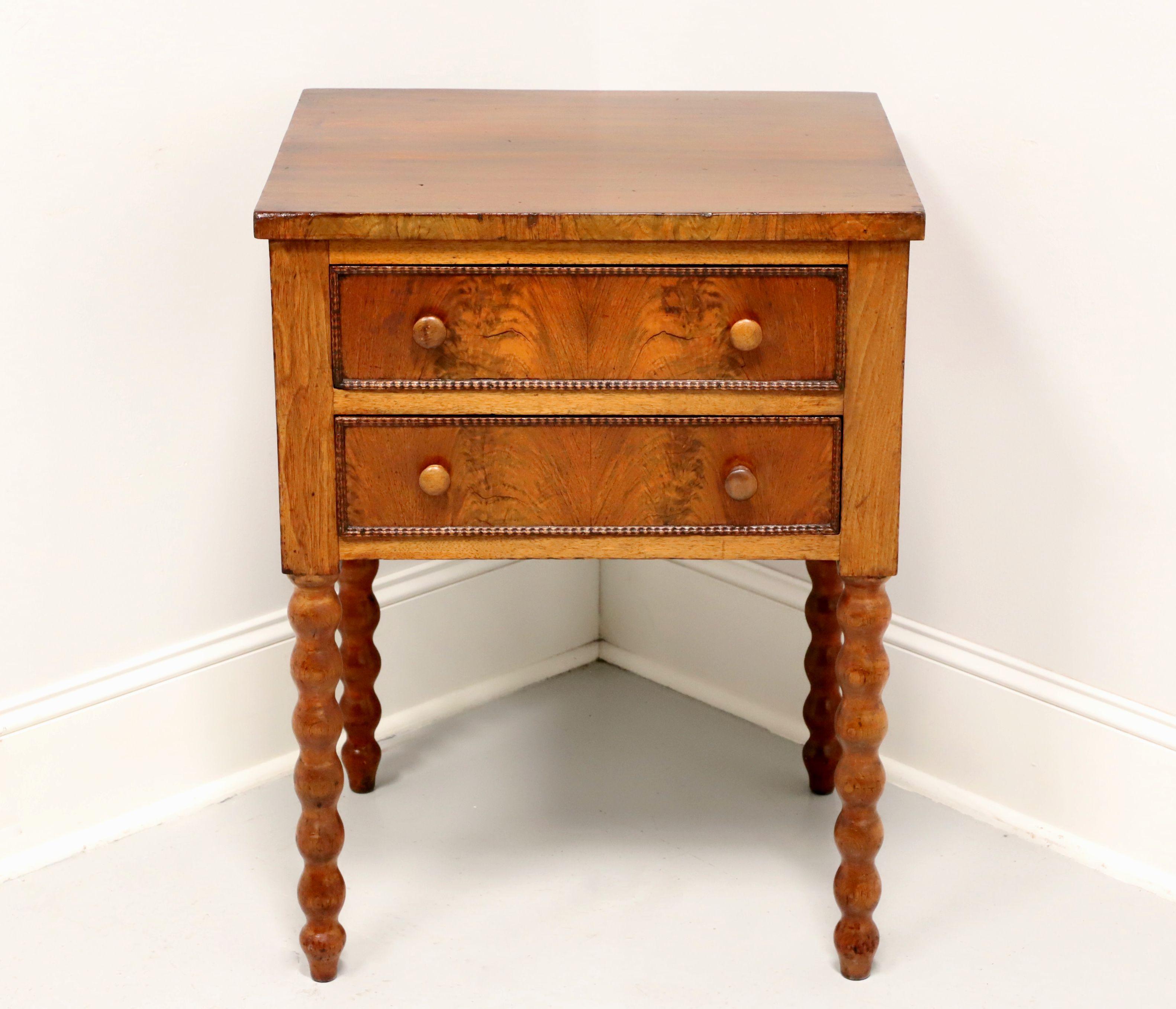 An antique side table from the Victorian era, unbranded. Handcrafted of walnut with burl to drawer fronts, polished wood knobs and bobbin like legs. Features two drawers of dovetail construction. Likely made in England, in the 19th