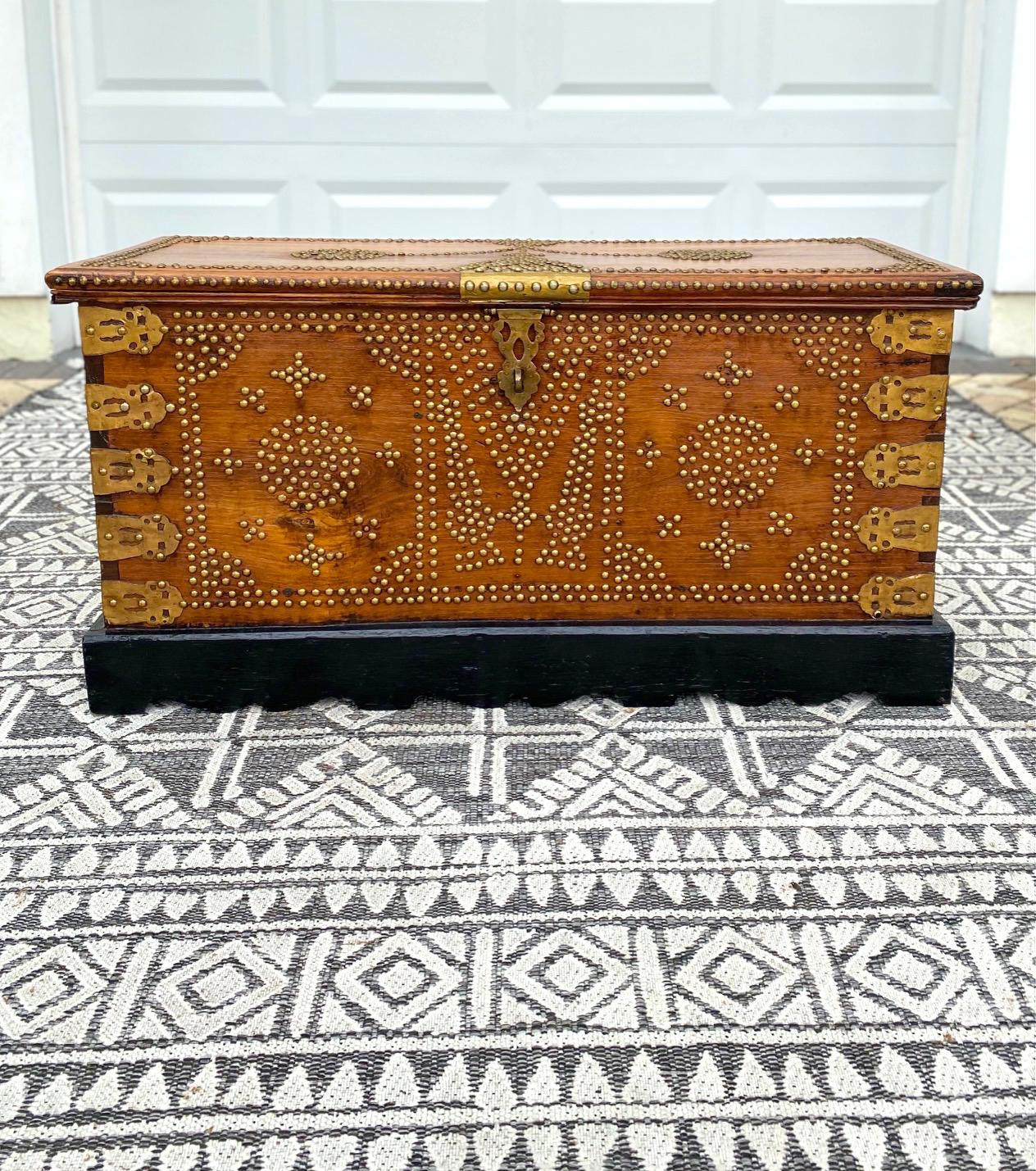 Rare early 20th century handcrafted Zanzibar blanket chest with brass metal overlay and brass studs throughout. The antique trunk is comprised of solid carved teak wood and features ornate brass interior hinges. The interior is also fitted with a