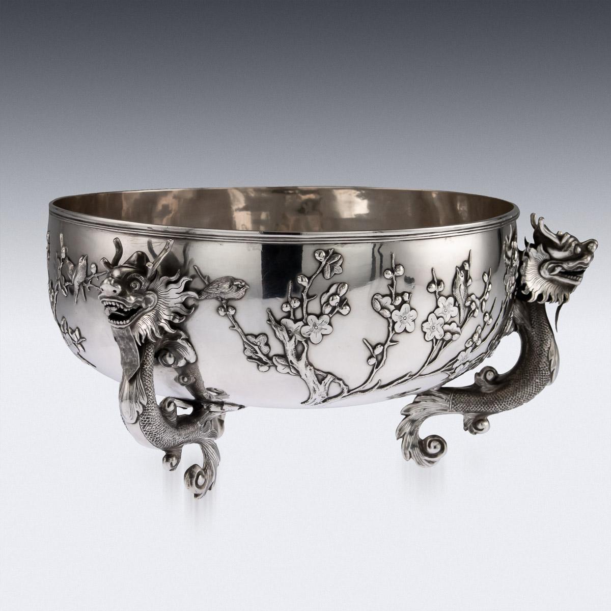 Antique late 19th century Chinese solid silver decorative dragon bowl, of round form with a deeded rim, plain ground applied, depicting birds flying and perched on blossoming cherry trees, supported by three mythical dragons. The bowl is